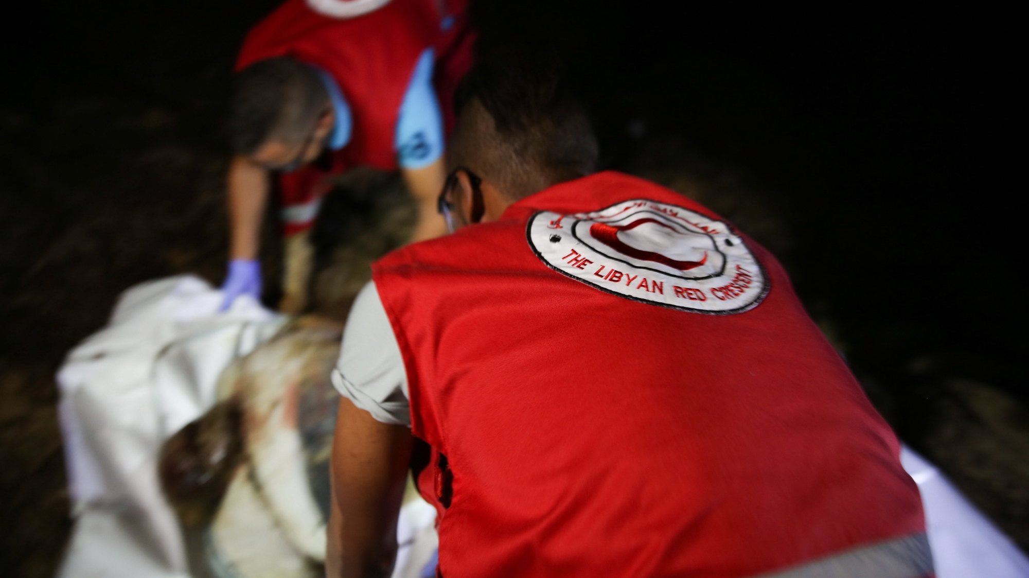 epa06860340 Libyan Red Crescent (LRC) rescue workers carry a body of a drowned migrant on a beach after being washed up, Tajoura, 14 kilometers east of Tripoli, Libya, 02 July 2018 (issued 03 July 2018). According to reports, Libyan rescuers found bodies of 17 drowned migrants over the past two days, after a migrant boat sank off the coast on 29 June with some 100 people missing in the incident.  EPA/STRINGER