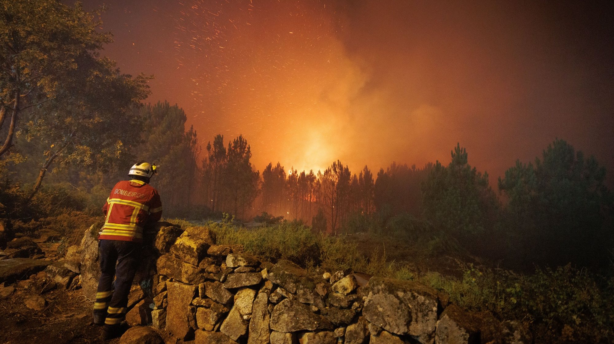 Um bombeiro observa as chamas durante o combate ao incêndio na aldeia de Escariz que se viu envolvida pelas chamas, esta tarde, em Vila Real, 21 de agosto 2022. PEDRO SARMENTO COSTA/LUSA