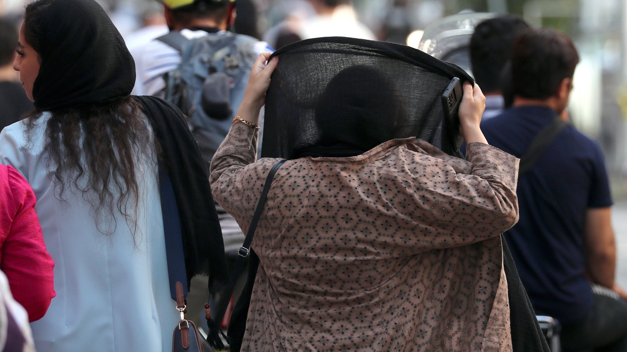 epa10793377 An Iranian woman adjusts her scarf as she walks in the street in Tehran, Iran, 10 August 2023. Iranâ€™s President Ebrahim Raisi on 09 August vowed that the Islamic Republicâ€™s mandatory dress code, including laws requiring women to wear the hijab, will be enforced. The statement came a month before the first anniversary of Mahsa Aminiâ€™s death in police custody, following her arrest for not wearing the hijab properly. Since then, a growing number of women in the country have been defying authorities by removing the headscarf.  EPA/ABEDIN TAHERKENAREH