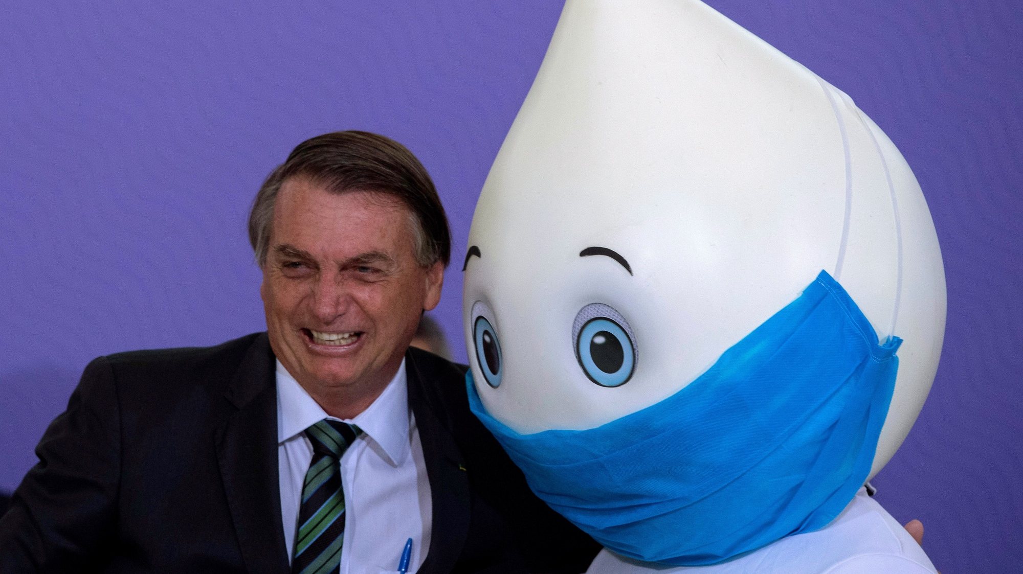 epaselect epa08887785 Brazilian President Jair Bolsonaro poses for photos with the mascot Ze Gotinha, a traditional character in Brazil created to raise awareness about vaccines, during the launch of the National Vaccination Plan against covid-19, at the Planalto Palace in Brasilia, Brazil, 16 December 2020. The Brazilian Government presented the master lines of its future vaccination plan against covid-19, which plans to immunize 210 million inhabitants in about 16 months, but has not yet set a start date for the process. According to the Ministry of Health, to establish the day on which the first of the five planned vaccination phases will begin, one must wait for an antidote to be approved and registered by the National Health Surveillance Agency (Anvisa), which could occur for next February.  EPA/Joedson Alves