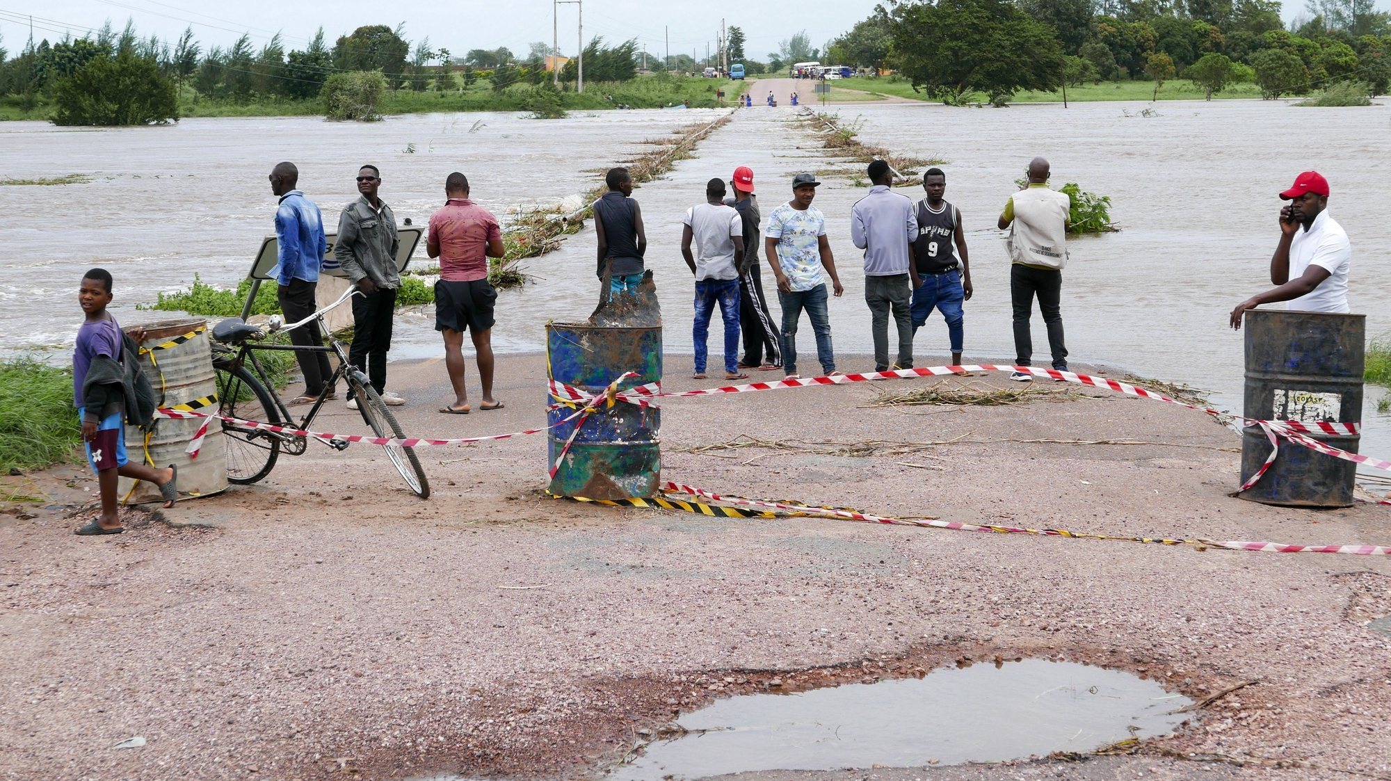 epa09016688 People watch the flooded area of Umbeluzi river due to the heavy rains of the last few days, leaving the bridge linking the district headquarters underwater, the town of Boane, 40 kilometers from the capital Maputo, Mozambique, 16 February 2021. The forecasts point to an improvement of atmospheric conditions in the south of the country from 17 February without rain and with the return of the sun.  EPA/LUISA NHANTUMBO