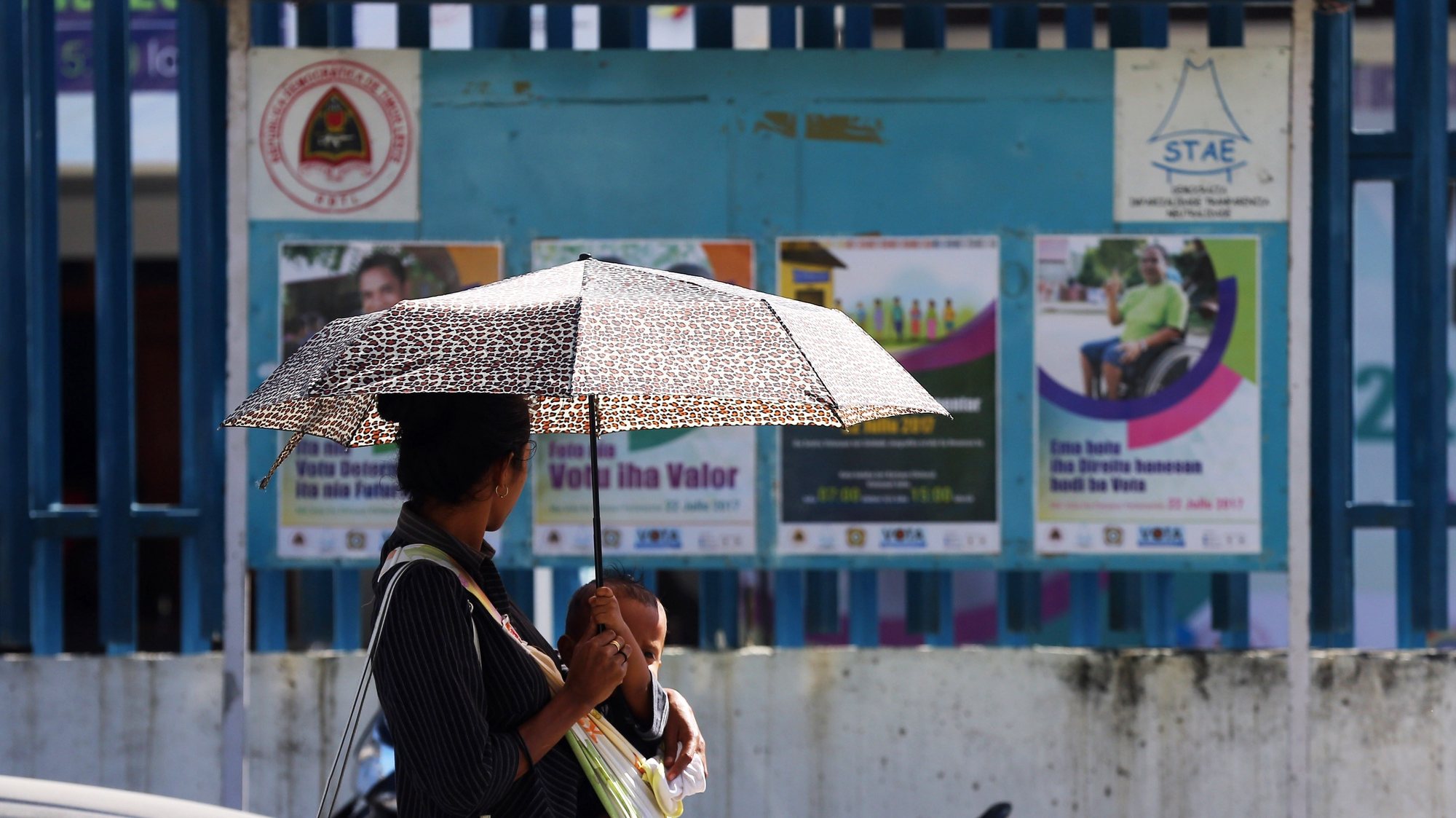 Uma timorense passa pelos cartazes de apelo ao voto, colocados à porta do edifício do Secretariado Técnico de Administração Eleitoral (STAE), no centro de Díli, enquanto decorre a campanha eleitoral para as eleições legislativas de dia 22 de julho, Dili, Timor-Leste, 11 de julho de 2017. NUNO VEIGA/LUSA
