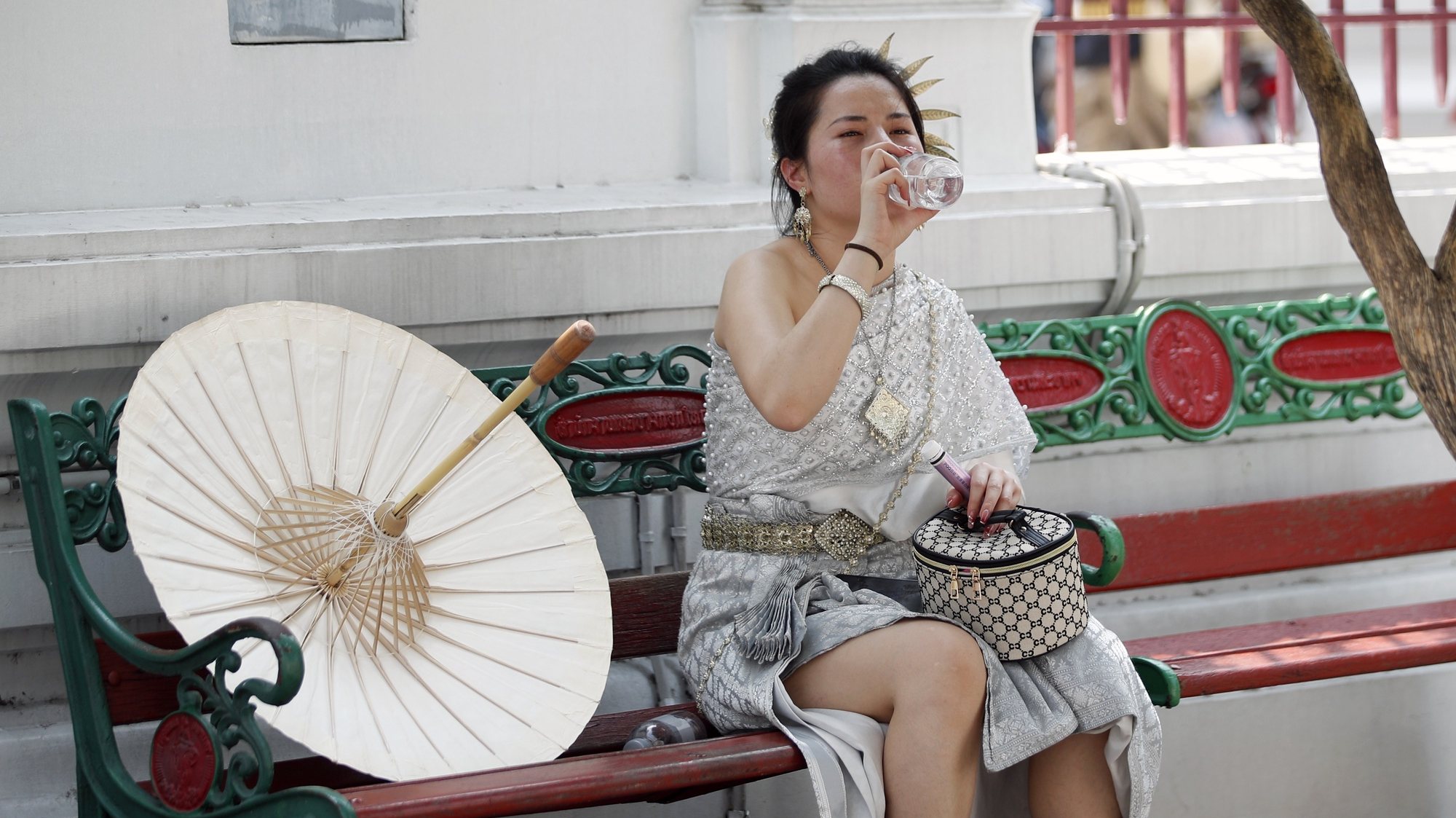 epa11321379 A Chinese tourist dressed in Thai traditional rented costume drinks water during hot weather at the Temple of Dawn or Wat Arun in Bangkok, Thailand, 06 May 2024. Thailand is facing a severe heatwave as the Thai Meteorological Department warned about the extremely hot weather with temperatures soaring to record highs over 44 degrees Celsius in some areas and advised the public to avoid prolonged outdoor activities from a highly dangerous heat level index that directly hazardously affects health conditions. A total of 38 people have been reported dead of heatstroke in Thailand from February to May 2024, according to Dr Atthapol Kaewsamrit, Deputy Director-General of the Health Department. The United Nations revealed in its recent report that Asia was identified as the global disaster center and anticipated to be significantly affected by climate related disruptions such as extreme temperatures, severe heatwave, floods, storms and melting glaciers.  EPA/RUNGROJ YONGRIT