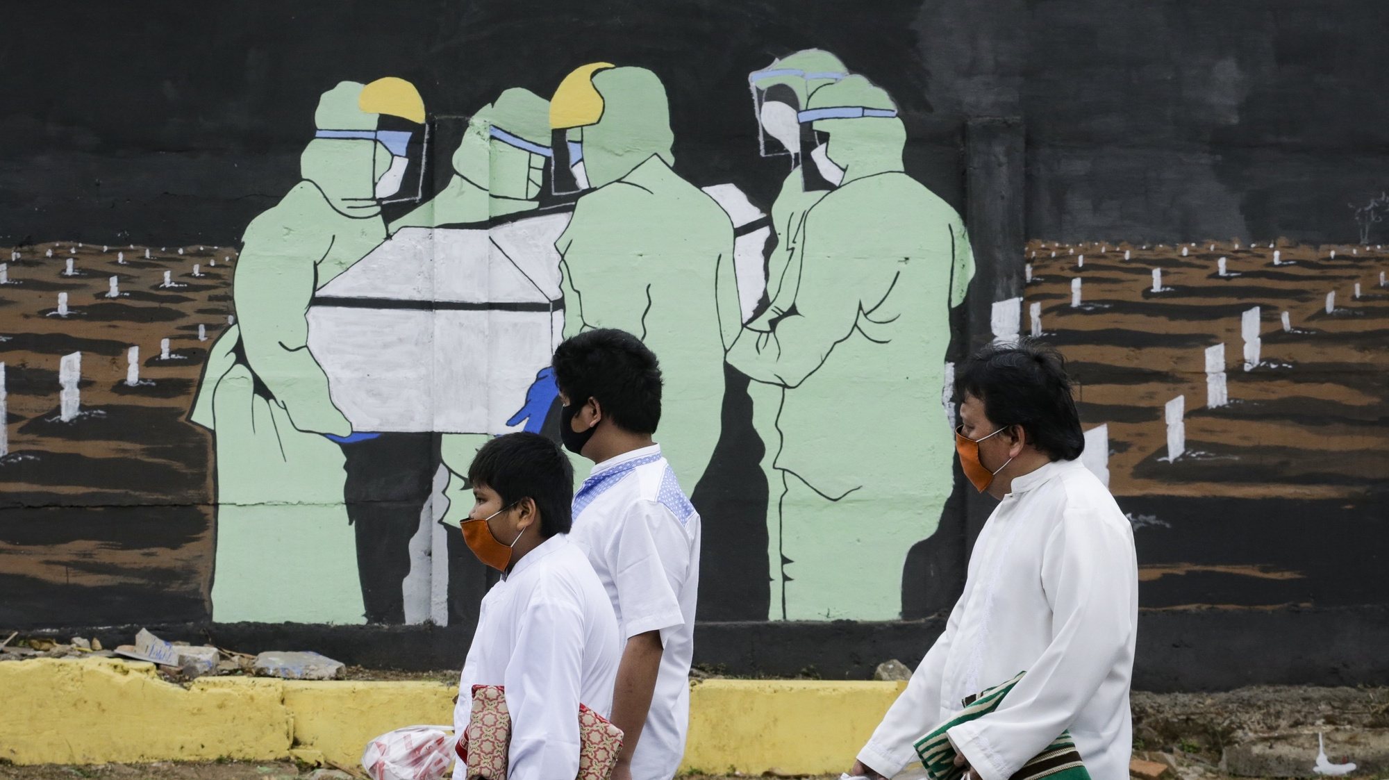 epa08660799 People wearing protective face masks walk past a mural showing the burial of a coronavirus victim in Jakarta, Indonesia, 11 September 2020. Jakarta&#039;s authorities have decided to reimpose the large-scale coronavirus restrictions, locally known as &#039;PSBB&#039; amid a rise in COVID-19 daily infections. The capital city will return to local lockdown on 14 September.  EPA/MAST IRHAM