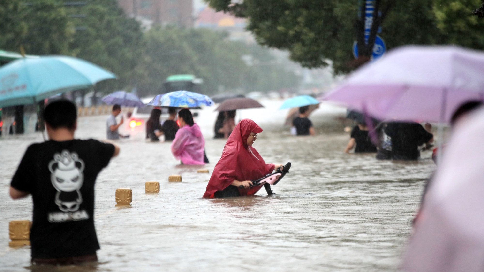 epa09356174 People walk in the flooded road after record downpours in Zhengzhou city in central China&#039;s Henan province Tuesday, July 20, 2021 (issued 21 July 2021). Heavy floods in Central China killed 12 in Zhengzhou city due to the rainfall yesterday, 20 July 2021, according to official Chinese media. Over 144,660 people have been affected by heavy rains in Henan Province since July 16, and over 10,000 had to be relocated, the provincial flood control and drought relief headquarters said Tuesday.  EPA/FEATURECHINA CHINA OUT