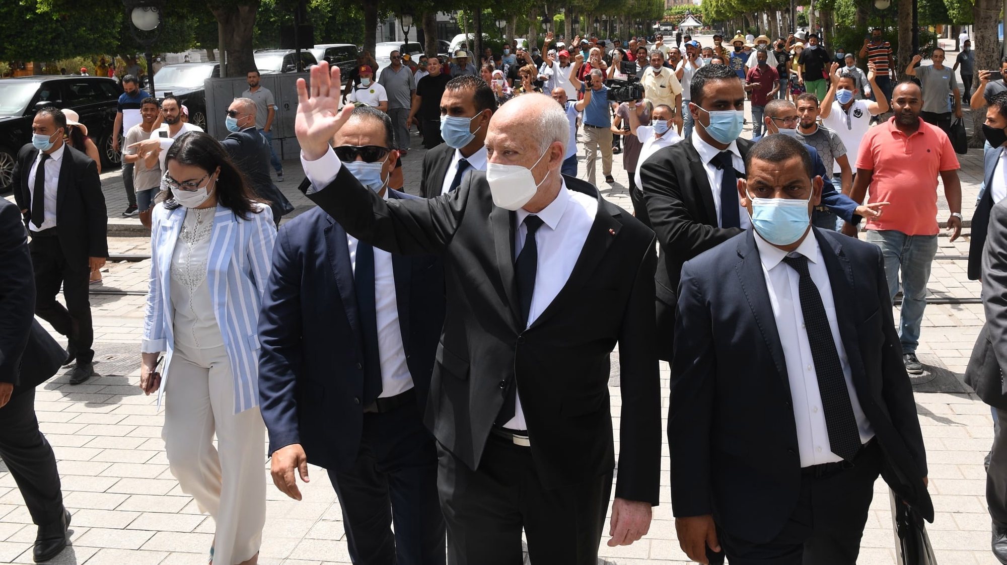 epa09386130 A handout photo made available by the Tunisian Presidency shows Tunisian President Kais Saied (C) gesturing among supports as he walks protected by security guards in Habib Bourguiba Avenue, Tunis, Tunisia, 01 August 2021. Two Members of the Parliament were reportedly arrested on 01 August brining to three the number of MPs detained since Saied sacked prime minister Mechichi and suspended the parliament on 25 July. Saied said he acted within the constitution as US Secretary of State Antony Blinken called for the return &#039;to the democratic path&#039; in the country.  EPA/PRESIDENCY OF TUNISIA HANDOUT  HANDOUT EDITORIAL USE ONLY/NO SALES