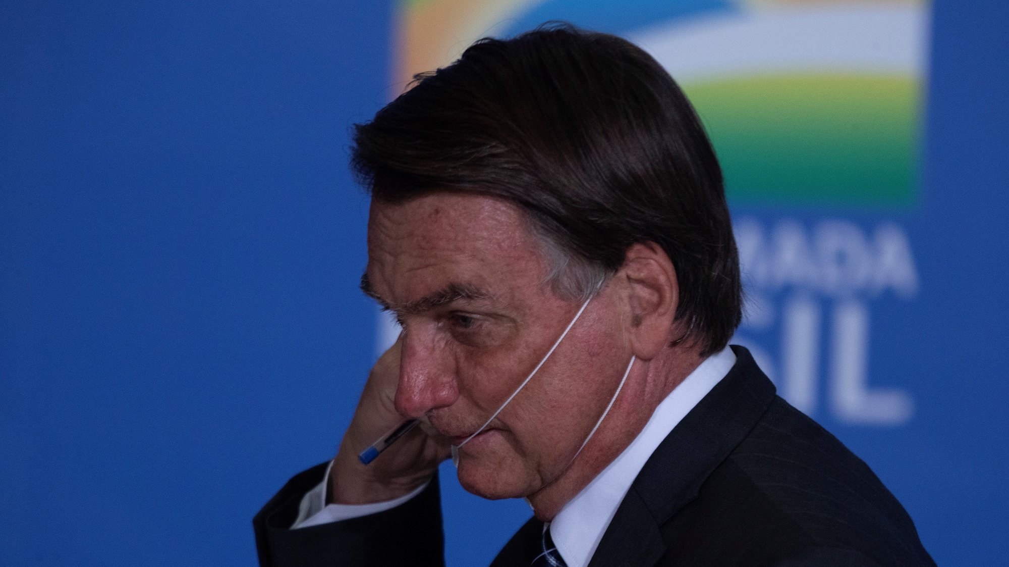 epa09294580 Brazilian President Jair Bolsonaro removes his face mask during the launching of an agriculture program at Planalto Presidential Palace in Brasilia, Brazil, 22 June 2021. Brazil&#039;s Goverment announced some US $50 billion for investments in agriculture during 2021-2022.  EPA/JoÃ©dson Alves