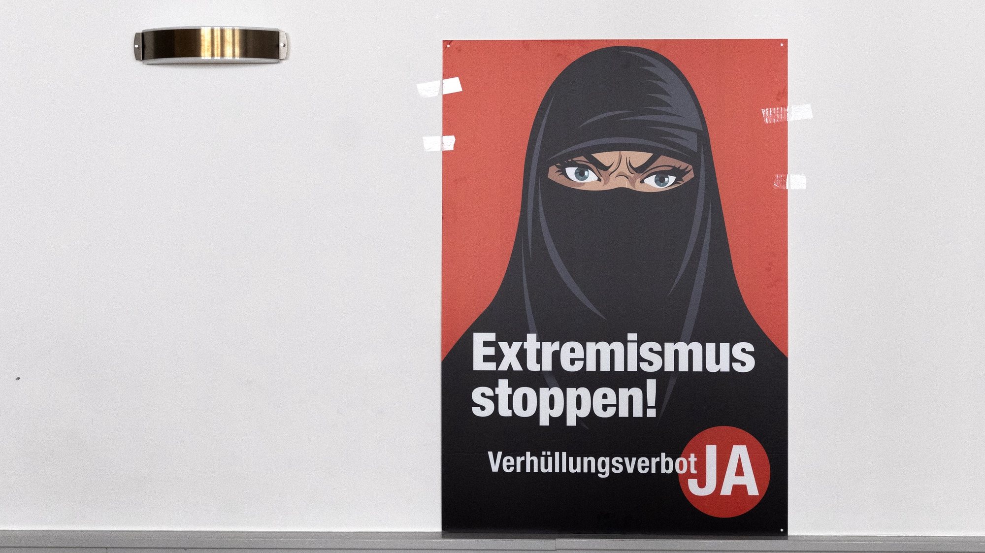 epa09059579 A poster &#039;Stop Extremism&#039; hangs on a wall at the meeting place of the supporters of the Burqa Ban initiative, in Bern, Switezrland, 07 March 2021. Swiss citizens vote on a proposal to prohibit the concealment of one&#039;s face in the public space. Led by right-wing groups, the so-called &#039;anti-burqa&#039; initiative provides for a ban on the wearing of the niqab, as well as other non-religious forms of face concealment.  EPA/PETER KLAUNZER
