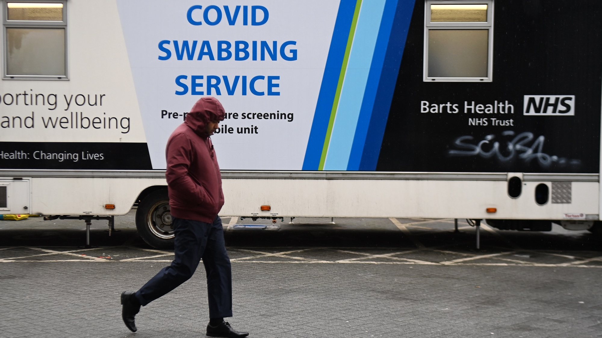 epa09021521 A pedestrian walks past a mobile Covid-19 test centre in London, Britain, 18 February 2021. Hospital admissions and deaths from Covid-19 are dropping significantly, according to reports. The UK government is hopeful that schools can reopen in early March and that lockdown restrictions can start to be lifted.  EPA/ANDY RAIN