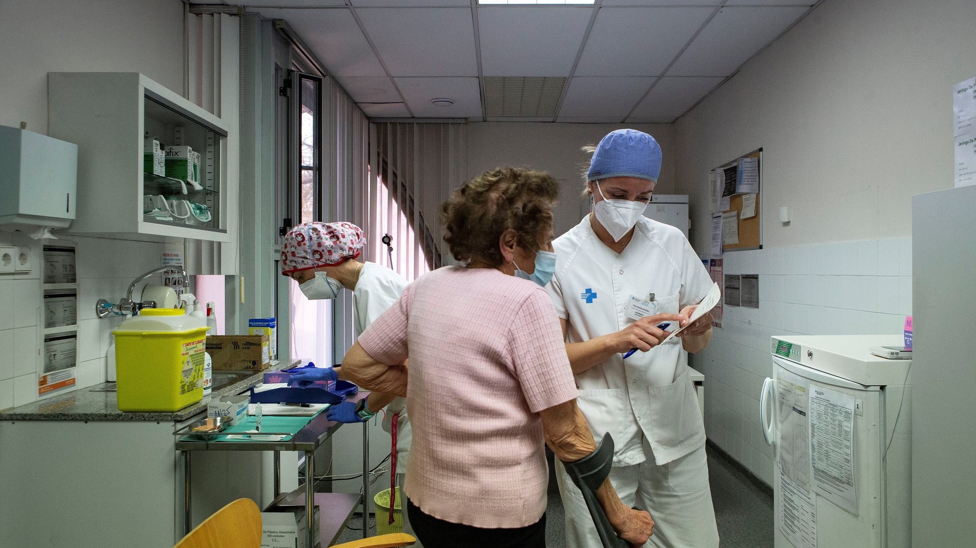 epa09048674 A nurse (R) chats with an elderly lady at a public health center during the vaccination campaign for people older than 80 years, in Barcelona, Catalonia, Spain, 03 March 2021. Although the number of coronavirus cases continue falling in the region, a total of 1,559 new COVID-19 cases and 44 fatalities were recorded in last 24 hours.  EPA/ENRIC FONTCUBERTA