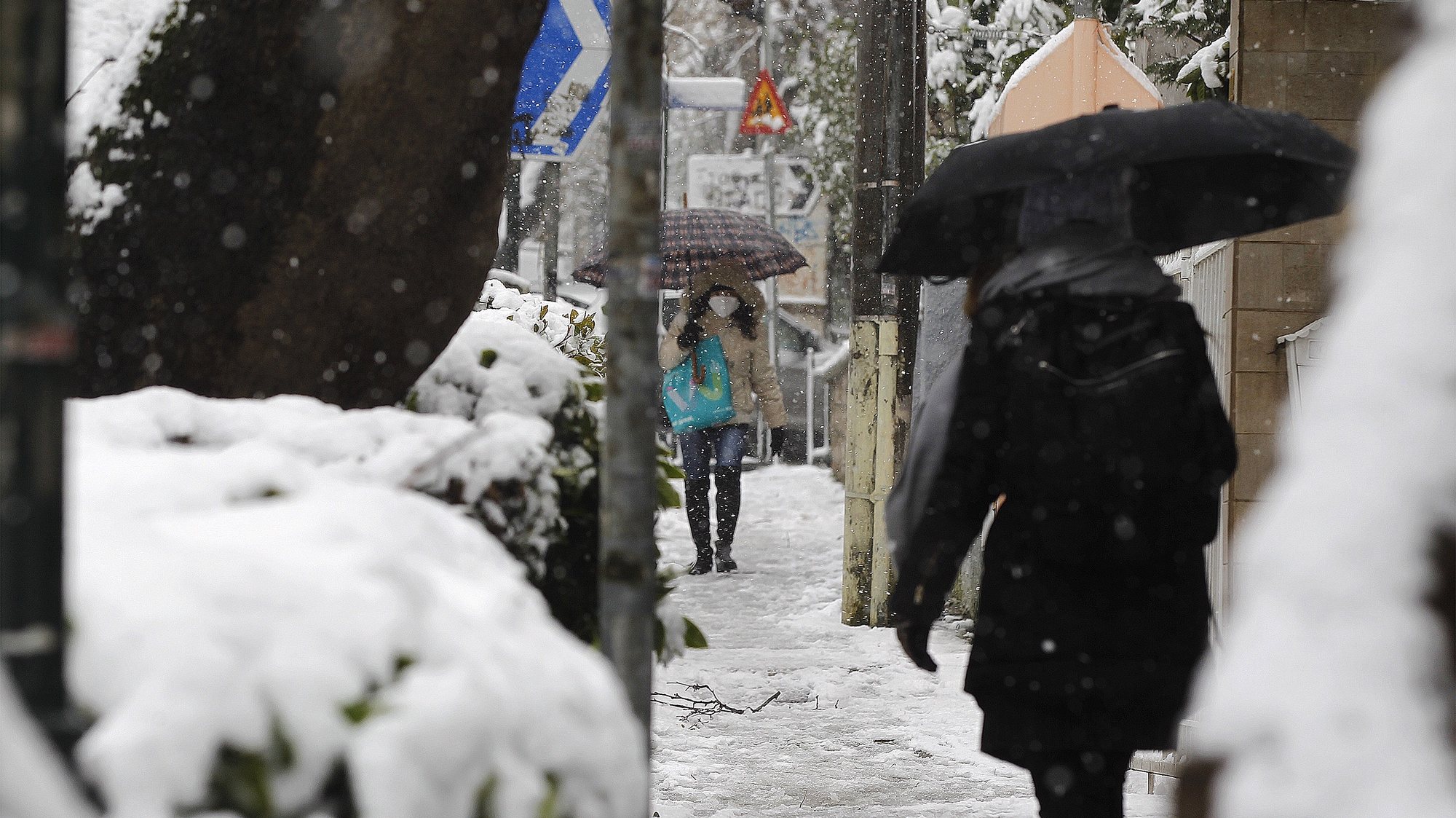 epa09014439 Women walk on a street during a heavy snowfall in northern Athens, Greece, 15 February 2021.  The first wave of the Medea weather system was fully underway in Greece on 14 February, bringing snow to many parts of the country, with the northern suburbs of Attica expected to see snow fall from 14 February afternoon. According to the National Observatory of Athens weather service, quite heavy snow is expected in Central and northern Greece, as well as at higher altitudes.  EPA/ALEXANDROS VLACHOS