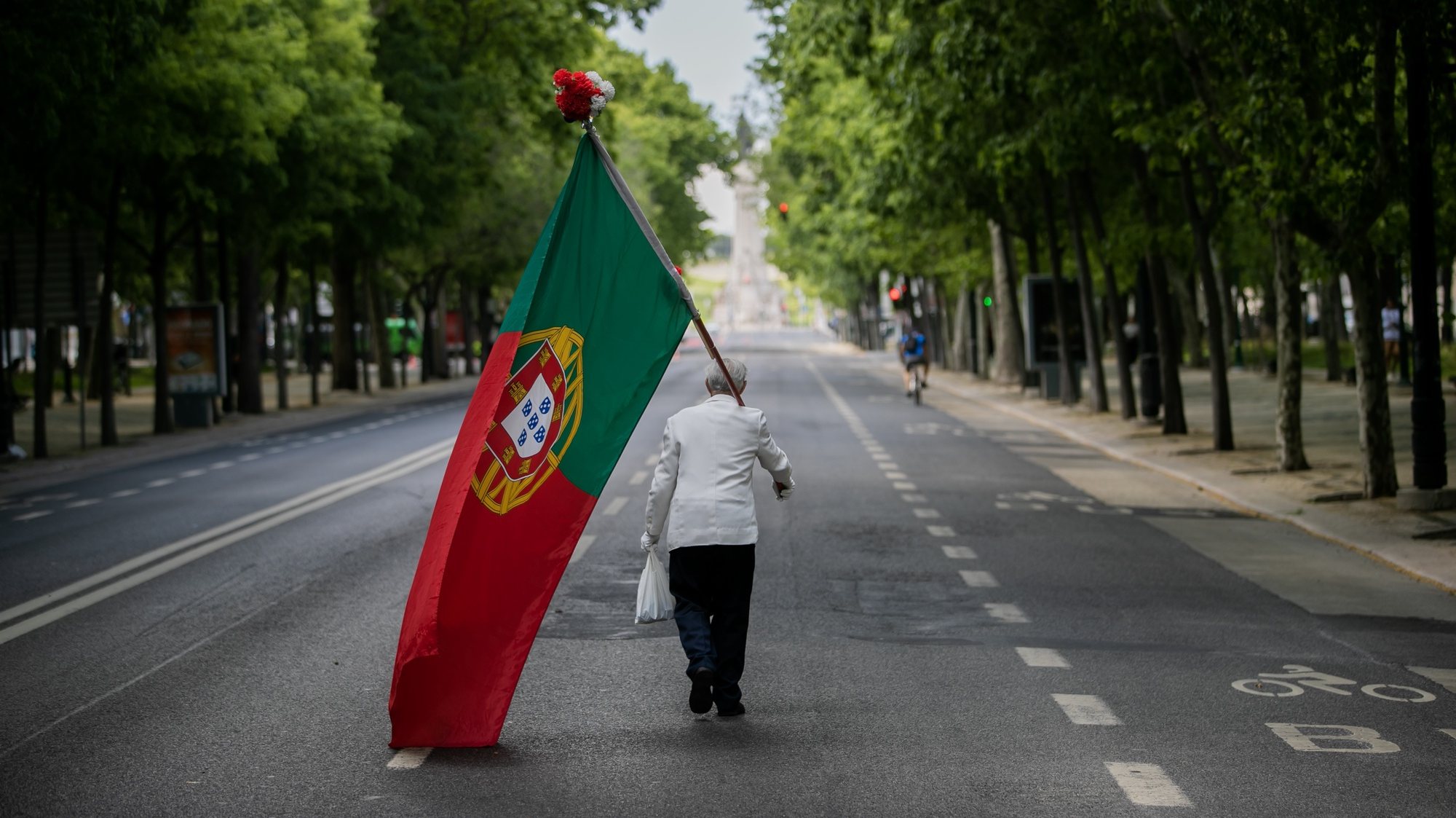 CONJUNTO DE 30 FOTOGRAFIAS SOBRE UM ANO DE ESTADO DE EMERGÊNCIA: 16-30: Foto datada de 25/04/2020: Um homem com uma bandeira de Portugal sobe a Avenida da Liberdade em Lisboa, por volta das 15 horas, altura em que anualmente se realiza um desfile comemorativo do 25 de abril de 1974 e que, devido à pandemia da covid-19, não pode ter lugar, em Lisboa, 25 de abril de 2020. Os 46 anos do 25 de Abril estão a ser hoje celebrados de forma diferente em Portugal, com uma sessão solene reduzida no parlamento, sem o tradicional desfile e com um apelo para que os portugueses cantem a ‘Grândola&#039; à janela. JOSÉ SENA GOULÃO/LUSA