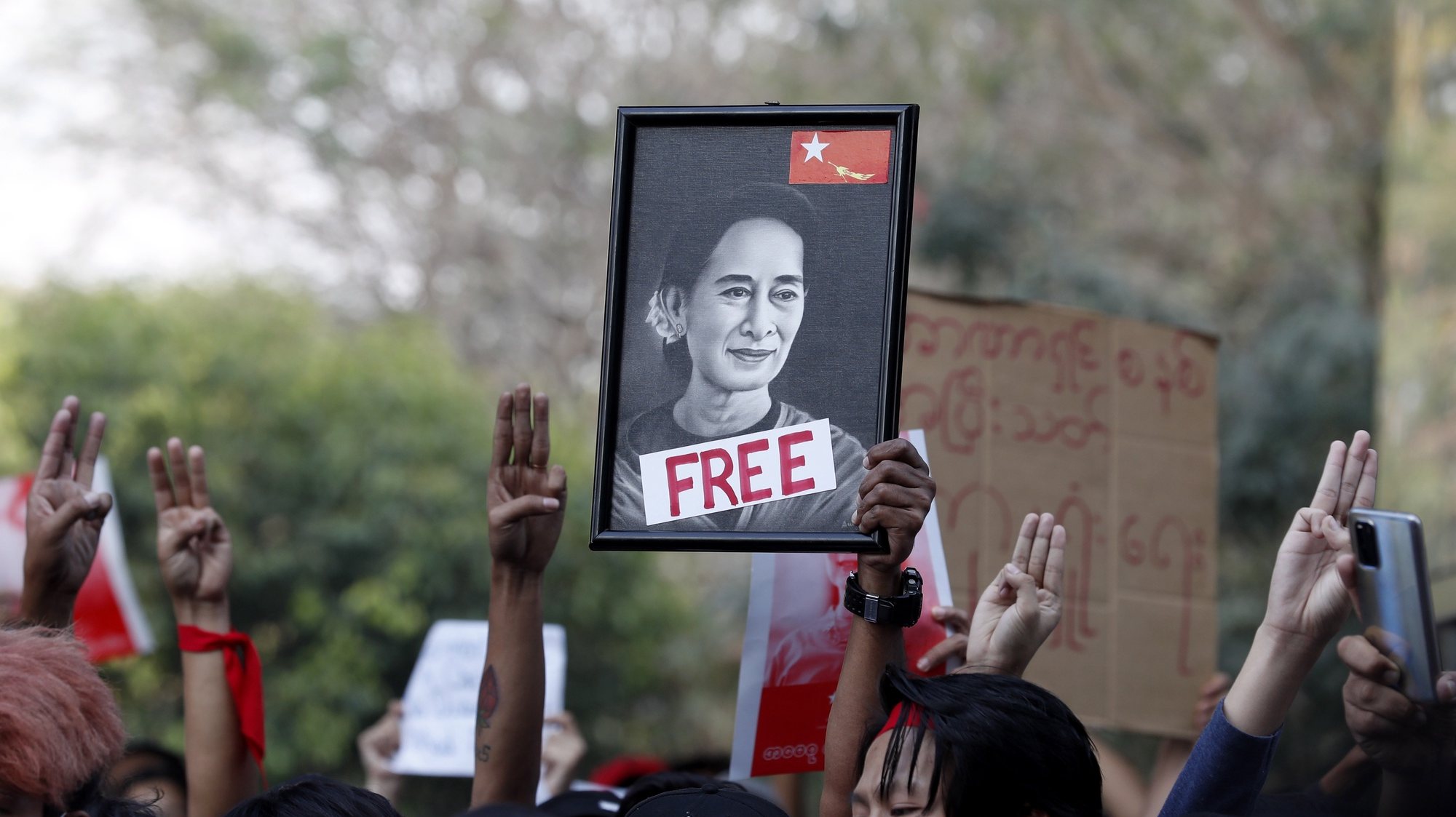Manifestantes erguem cartaz com a figura de Aung San Suu Kyi