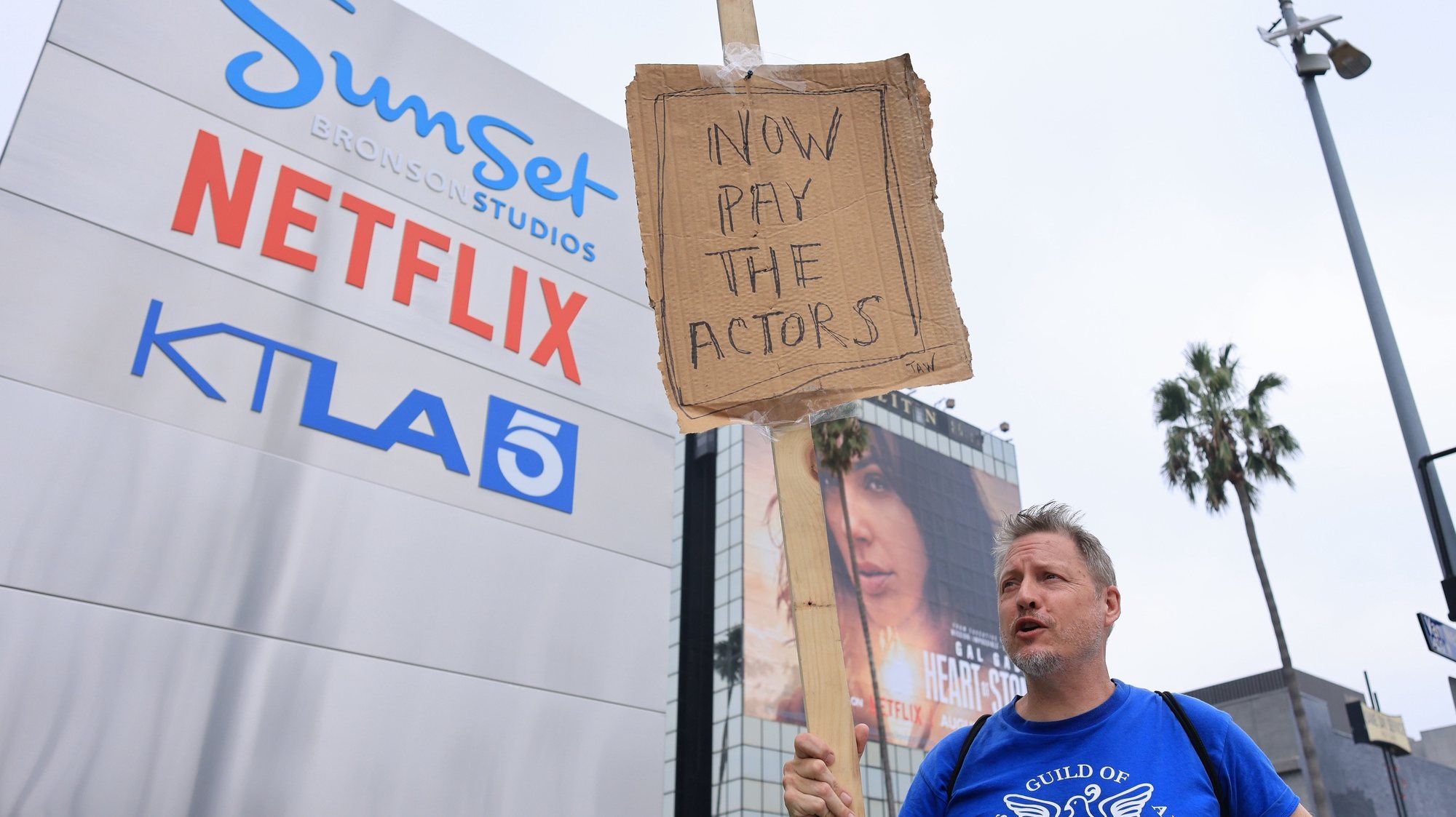 epa10882880 US screenwriter Travis Adam Wright, supporting the Screen Actors Guild, walks with a homemade sign in front of Netflix in Hollywood, California, USA, 25 September 2023. The Writers Guild of America (WGA) reached a tentative agreement to end the writers strike in Los Angeles.  EPA/DAVID SWANSON