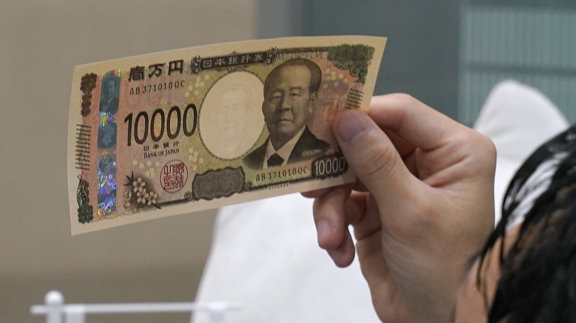 epa11454126 Atsuya Haramoto, a 28-year-old company salesman, inspects the 3D holography for anti-counterfeit measures on a new 10,000 Japanese yen note at Saitama Resona Bank headquarters in Saitama, north of Tokyo, Japan, 03 July 3, 2024. The Bank of Japan issued newly designed banknotes using the world&#039;s first holography on the bills for anti-counterfeit technology. The latest banknotes, the 10,000 Japanese yen, 5,000 Japanese yen, and 1,000 Japanese yen bills, were the first design changes in 20 years.  EPA/KIMIMASA MAYAMA