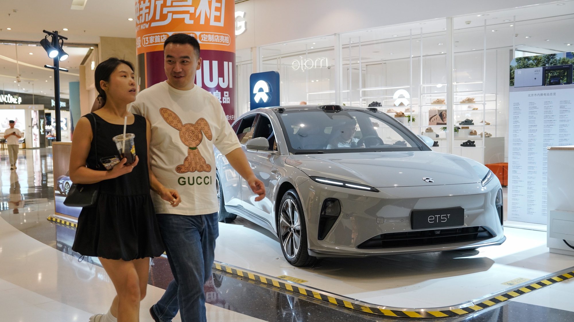 epa11407061 People walk beside a NIO ET5 electric car on display in a shopping mall in Beijing, China, 13 June 2024. Beijing urges the European Union to reconsider tariffs on Chinese electric vehicles and to stop going further in what they say is the &#039;wrong direction&#039; to protect its auto industry from competition, according to China&#039;s state news agency Xinhua. China said it would take measures to safeguard its interests after the European Commission announced on 12 June it would impose extra duties of up to 38.1 percent on imported Chinese electric vehicles from July 2024.  EPA/WU HAO