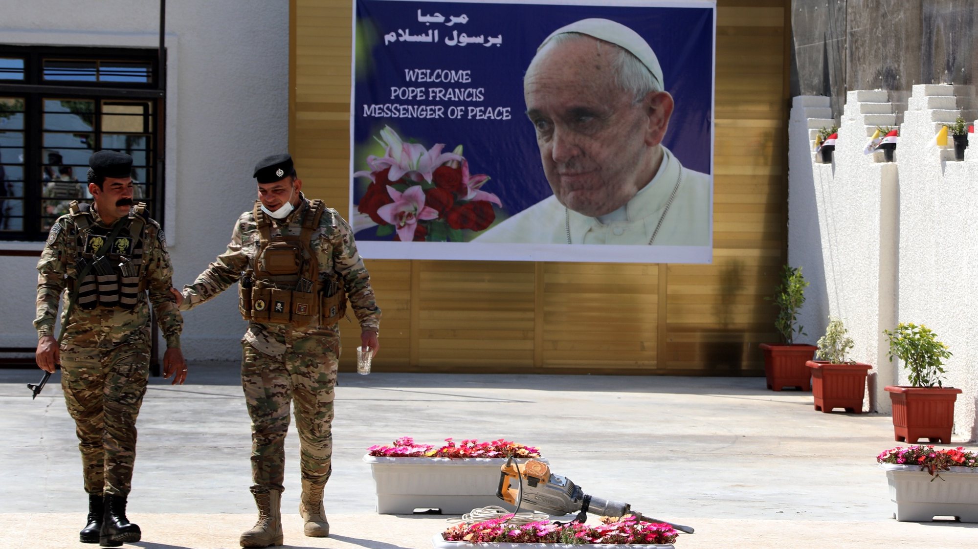 epaselect epa09044899 Iraqi policemen walk next to a posters depicting the picture of Pope Francis at the St. Joseph Chaldean Catholic Church in Baghdad&#039;s Karada district, Iraq on 01 March 2021. Pope Francis will visit St. Joseph church in Baghdad, during his trip to Iraq from 05 to 08 March 2021.  EPA/AHMED JALIL