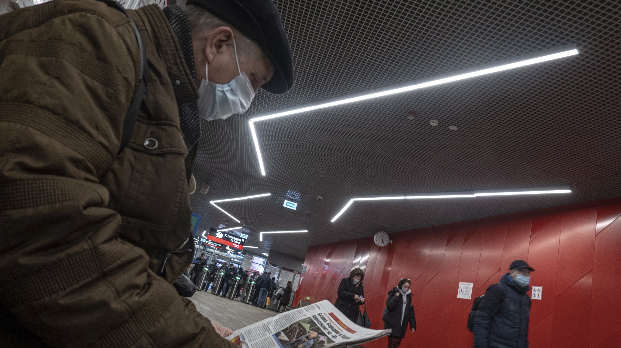 epa09117150 A man wearing a protective face mask reads a newspaper in a station of Moscow metro, Russia, 05 April 2021, amid the COVID-19 coronavirus pandemic.  EPA/SERGEI ILNITSKY
