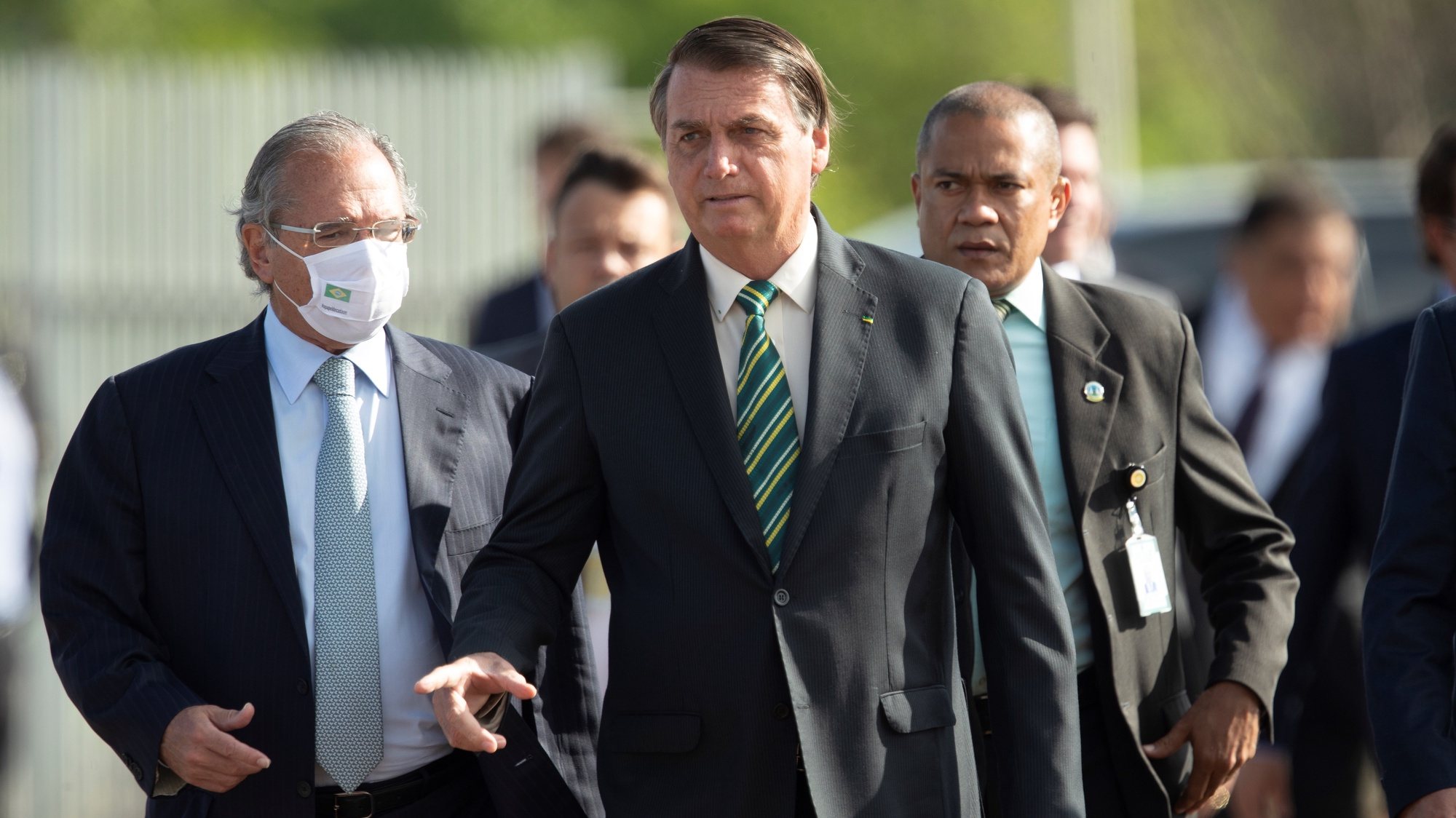 epa08777585 Brazilian President Jair Bolsonaro (C), walks with Economy Minister Paulo Guedes (L) towards the raising of the National Flag before the 38th Meeting of the Governing Council, at the Palace of the Alvorada, in Brasilia, Brazil, 27 October 2020.  EPA/Joedson Alves