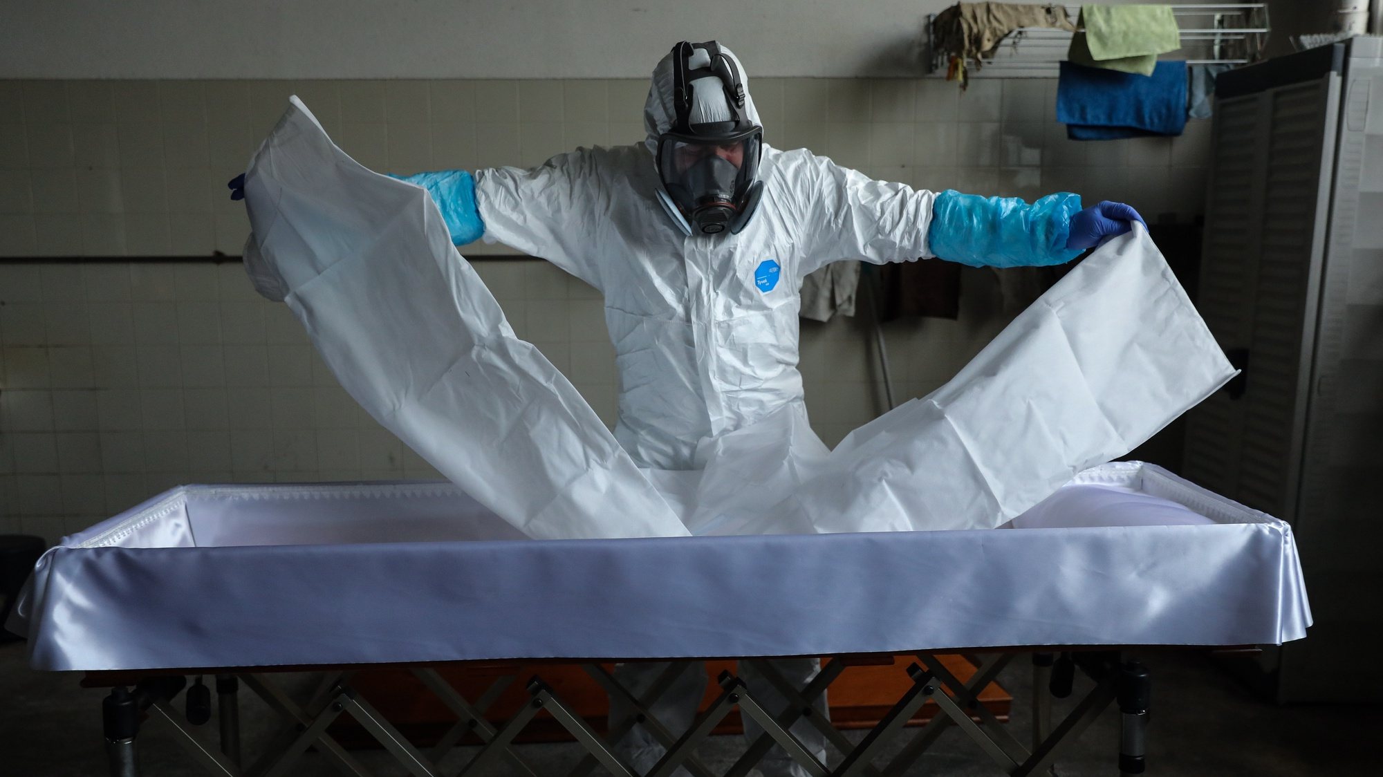epa08347889 An employee of a funeral home fully protected with a protective suit against radioactive contamination and biological agents, prepares a coffin for a body of a man over 80 years old who died in his home as a victim of covid-19, in Lisbon, Portugal, 03 April 2020 (Issued 07 April 2020). Portugal is in state of emergency until 17 April 2020. Countries around the world are taking increased measures to stem the widespread of the SARS-CoV-2 coronavirus which causes the Covid-19 disease.  EPA/MIGUEL A. LOPES  ATTENTION: This Image is part of a PHOTO SET