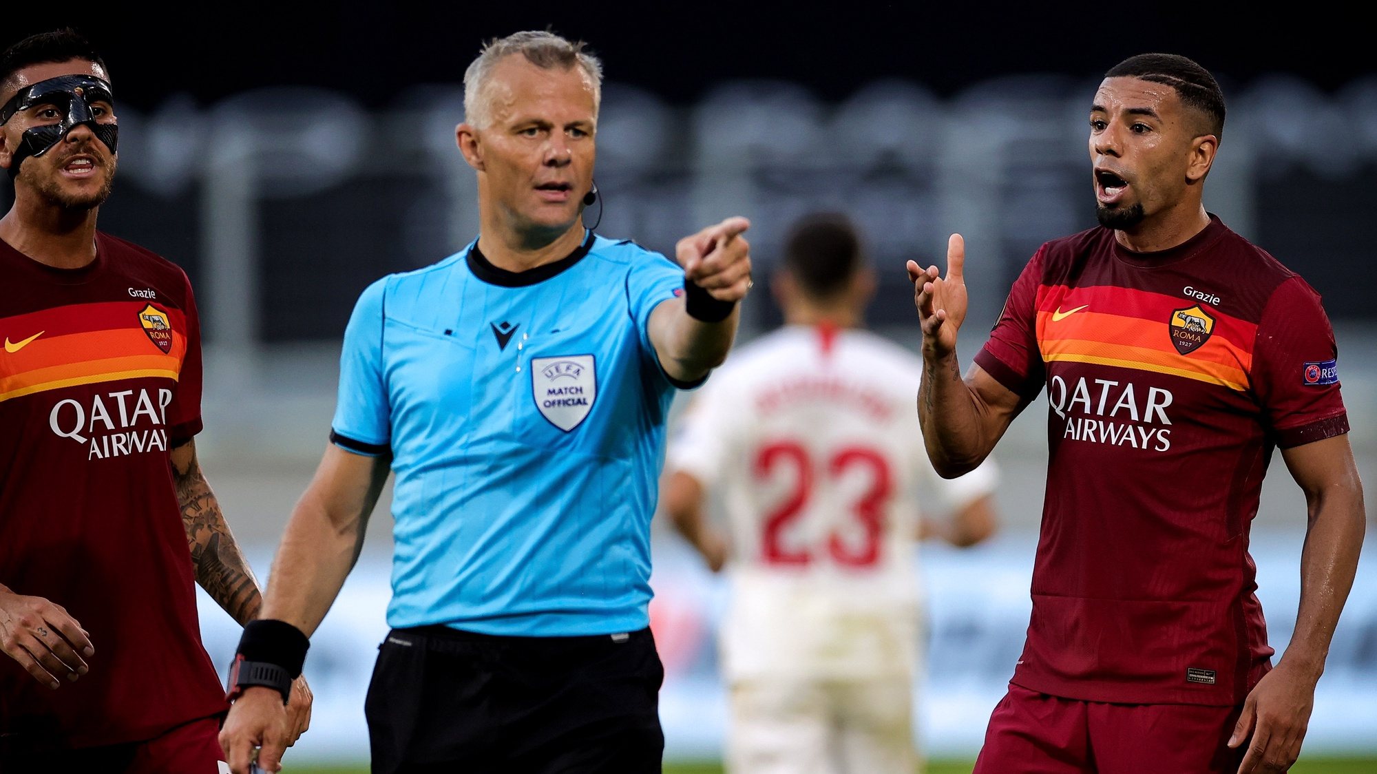 epa08588342 Roma’s Lorenzo Pellegrini (L) and Bruno Peres (R) argue with referee Bjorn Kuipers (C) during the UEFA Europa League Round of 16 soccer match between Sevilla FC and AS Roma in Duisburg, Germany, 06 August 2020.  EPA/Friedemann Vogel / POOL