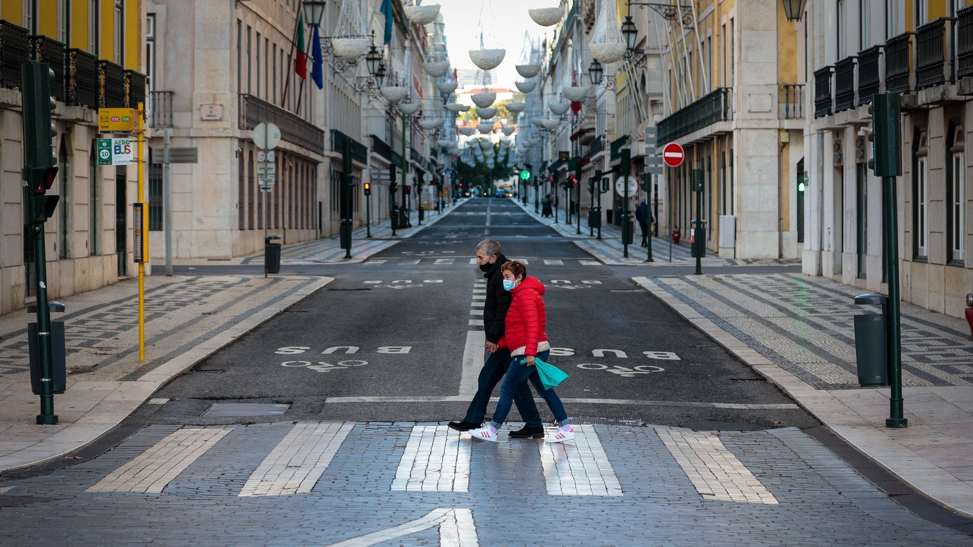 Um casal atravessa uma rua da baixa de Lisboa a meio da tarde, 05 de dezembro de 2020. Entre as 13:00h de sábado 05 de dezembro e as 05:00h de 06 dezembro, está em vigor o recolher obrigatório nos concelhos de risco &quot;extremamente elevado&quot; e &quot;muito elevado&quot;. JOSÉ SENA GOULÃO/LUSA