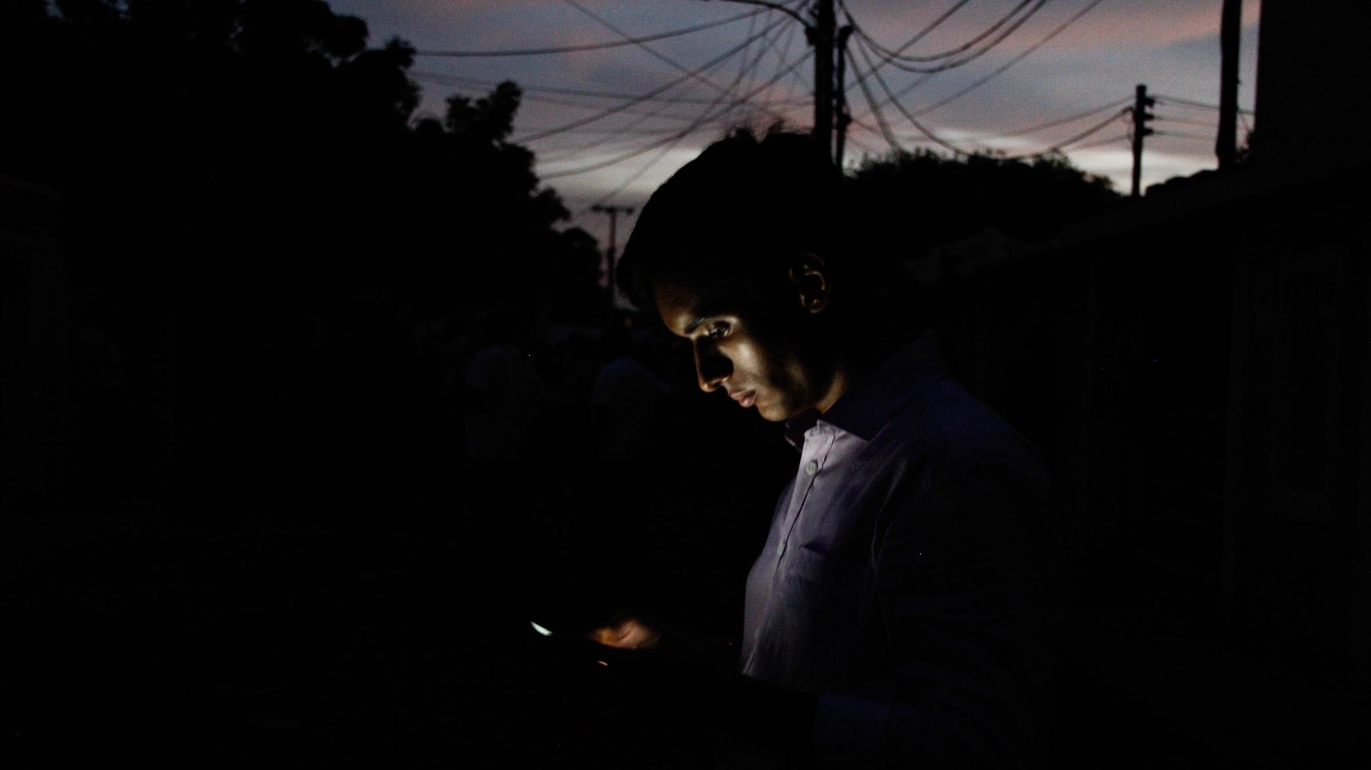 epaselect epa07858009 A man views his phone in a street without electricity due to the cut of service in Maracaibo, Venezuela, 20 September 2019. Several areas of Caracas and a dozen other Venezuelan states were left without electricity on 20 September afternoon, according to reports from users on social networks, although the state power company only recognizes breakdowns in specific urban areas of the capital and the neighboring state of Miranda.  EPA/HENRY CHIRINOS