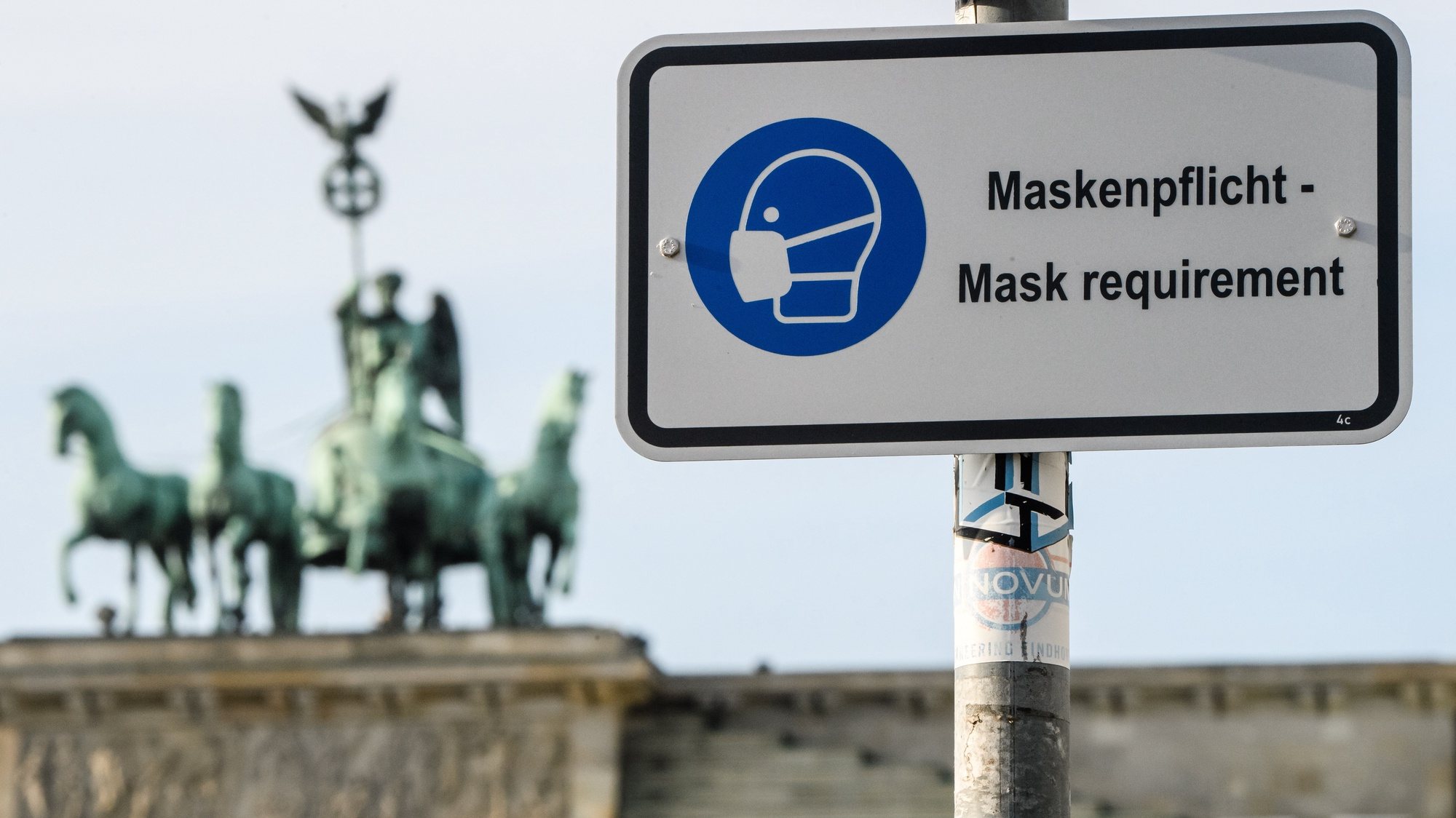 epa08966587 A road sign reading &#039;mask requirement&#039; is pictured in front of the Quadriga statue of the Brandenburg Gate in Berlin, Germany, 26 January 2021. Due to lockdown measures and contact restrictions, public places are less visited. Wearing face masks in Germany is, up to date, only mandatory in specific places and streets.  EPA/CLEMENS BILAN