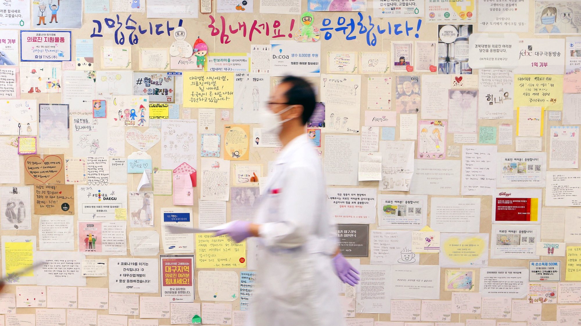 epa09660978 A doctor walks past a wall full of messages cheering medical workers grappling with Covid-19 at Kyungpook National University Hospital in Daegu, South Korea, 31 December 2021.  EPA/YONHAP SOUTH KOREA OUT