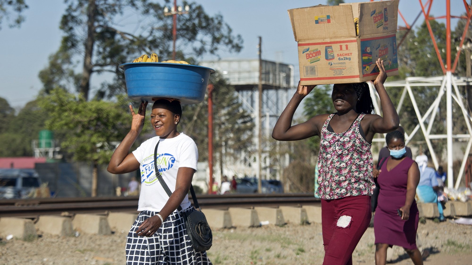 epa08757357 Women carrying goods on their heads walk in a street in Harare, Zimbabwe, 19 October 2020. According to the World Health Organisation (WHO), Africa faces a reality check in its fight against the coronavirus pandemic as cases and deaths rise after easing lockdowns and travel restrictions. The continent has seen an increase in weekly Covid-19 cases.  EPA/AARON UFUMELI