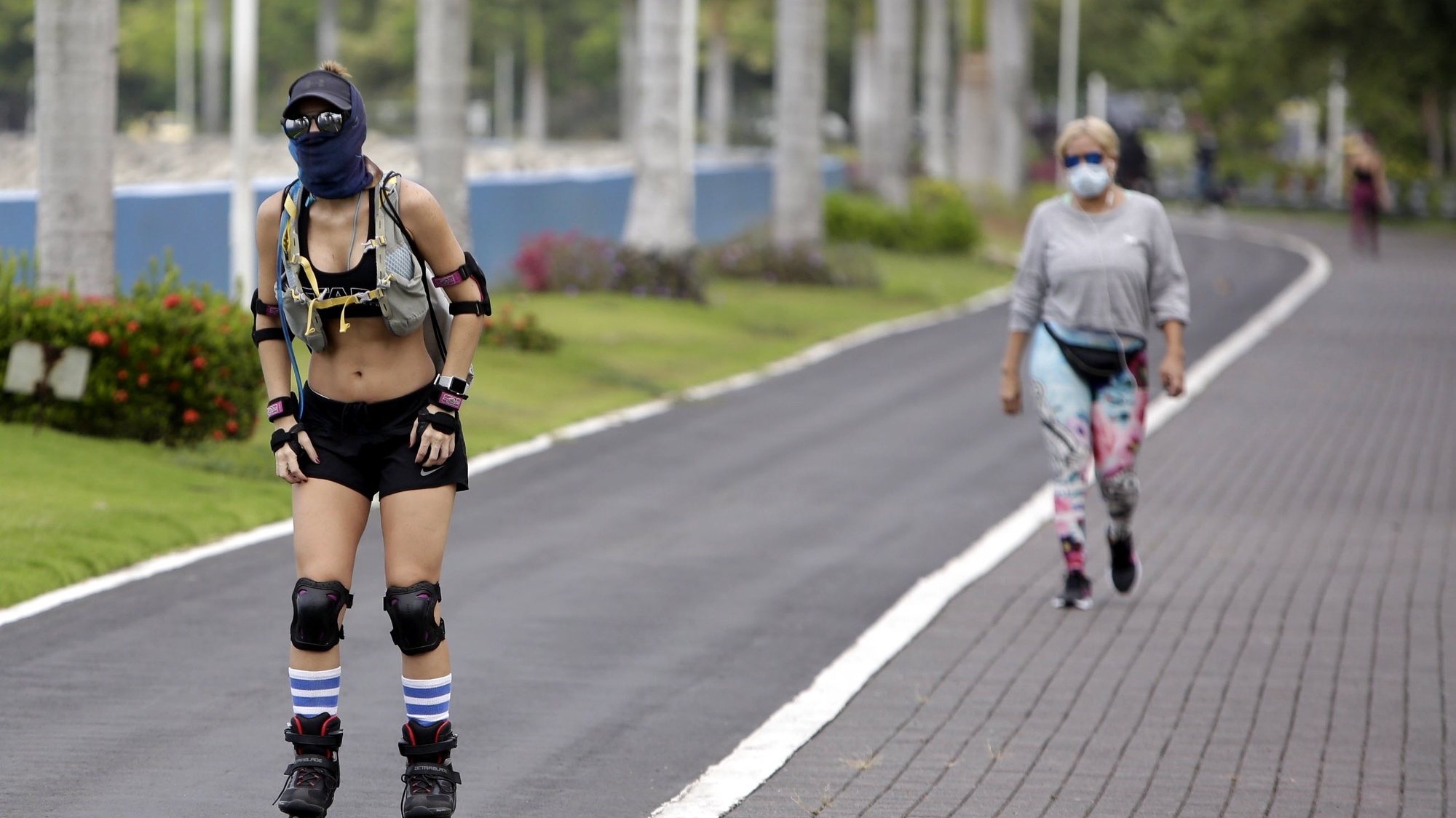 epa08430592 A woman skates in front of another who is walking on a roadway enabled for physical activity, in Panama City, Panama, 18 May 2020. The health authorities are beginning to relax the quarantine measures for the return to the new normality of the citizens, who from this Monday will be able to exercise individually in the open air, as long as they maintain the use of masks and social distancing. Panamanians will have only one kilometer of perimeter from their homes for said activity, the corresponding day according to the time and the numbering of their ID.  EPA/Carlos Lemos