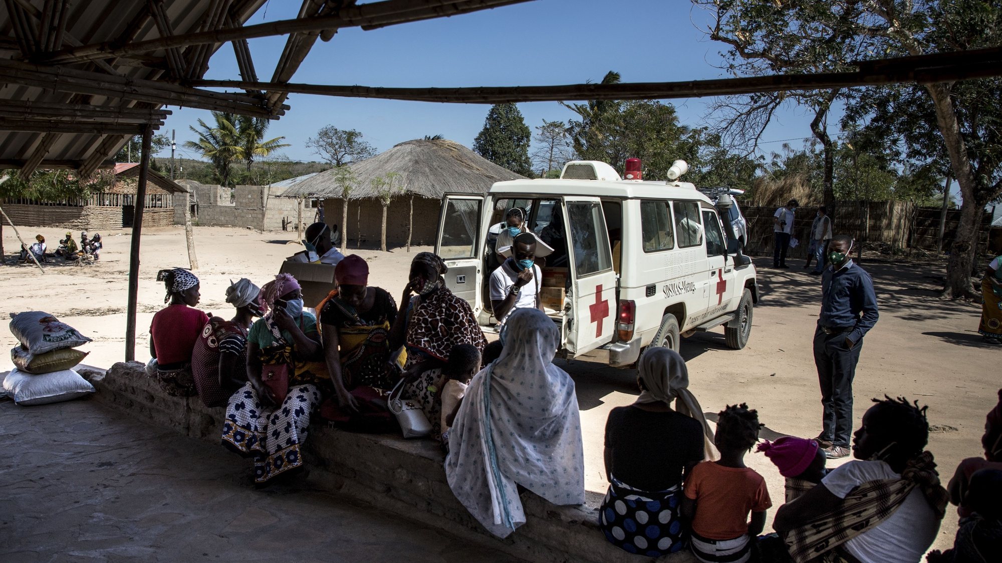 Mães com os seus filhos aguardam pela consulta de uma brigada móvel do Fundo das Nações Unidas para a Infância (UNICEF), um grupo de profissionais de saúde que viaja de ambulância e vai ao encontro das comunidades mais afastadas em vez de esperar por elas em centros de saúde, Impire, Moçambique, 24 de julho de 2020. Em menos de uma hora, na povoação de Impire, distrito de Metuge, sul de Cabo Delgado, juntam-se dezenas de mães com as suas crianças - a maioria ainda bebés - para a brigada observar, com pesagem, medição de altura, avaliação à subnutrição, seguindo-se uma consulta, vacinação e entrega da medicamentos numa rotina que inclui a observação das mães e decorre desde manhã até o sol se pôr, num pavilhão empoeirado. (ACOMPANHA TEXTO DE 25 DE JULHO DE 2020). RICARDO FRANCO/LUSA