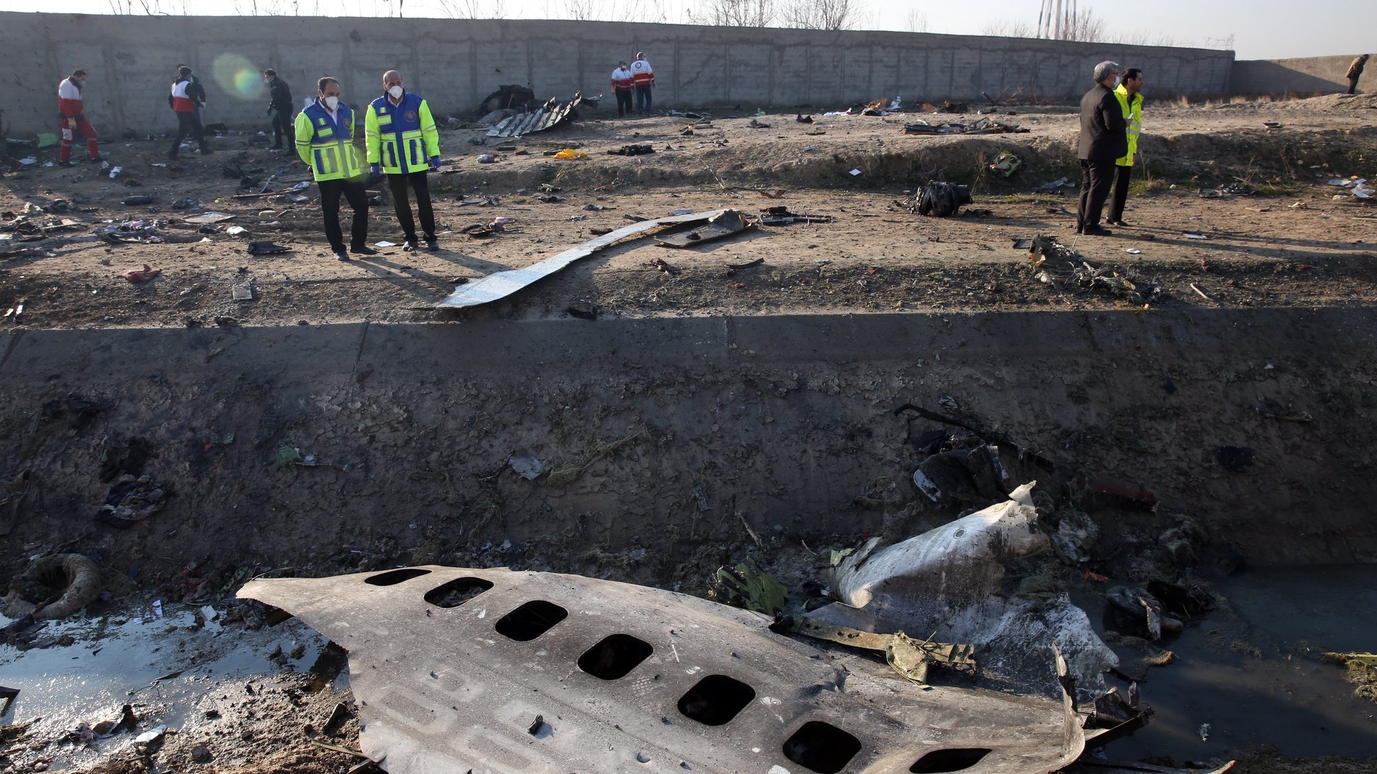epa08553428 (FILE) - Officials stand near the wreckage after an Ukraine International Airlines Boeing 737-800 carrying 176 people crashed near Imam Khomeini Airport in Tehran, killing everyone on board; in Shahriar, Iran, 08 January 2020 (reissued 18 July 2020). Media reports state on 18 July 2020 that Iran has sent to France the black box of the Ukrainian passenger plane, which was accidentally downed by Iranian armed forces on 08 January 2020 near Tehran, killing all 176 people aboard, after mistaking it for an incoming missile. The black box will be read in Paris on 20 July 2020, media added. *** Local Caption *** 55750844