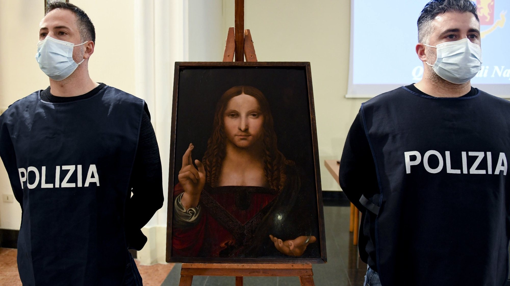 epa08948081 Two police officers stand next to the recovered painting &#039;Salvator Mundi&#039;, in Naples, southern Italy, 18 January 2021 (issued 19 January 2021). The 15th-century painting of Christ the Saviour from the school of Leonardo da Vinci, part of the &#039;DOMA&#039; collection, has been recovered by police during a search in Naples after it was stolen from the Basilica di San Domenico Maggiore in the southern Italian city two years ago. A 36-year-old, the owner of the flat, has been detain on suspicion of receiving stolen goods, media reported.  EPA/CIRO FUSCO
