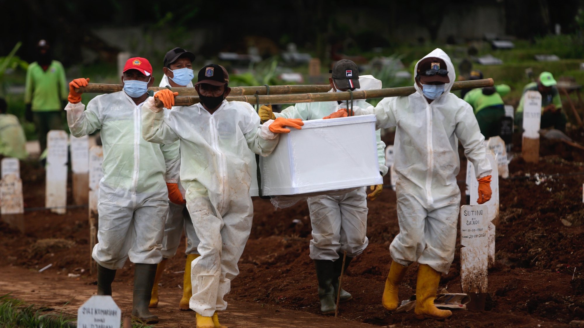epa08970591 Workers clad in hazmat suits carrying the coffin of a COVID-19 victim during a funeral at Bambu Apus Cemetery in Jakarta, Indonesia, 28 January 2021. Indonesia has reported more than one million COVID-19 cases since the beginning of the pandemic, the highest number in Southeast Asia.  EPA/ADI WEDA
