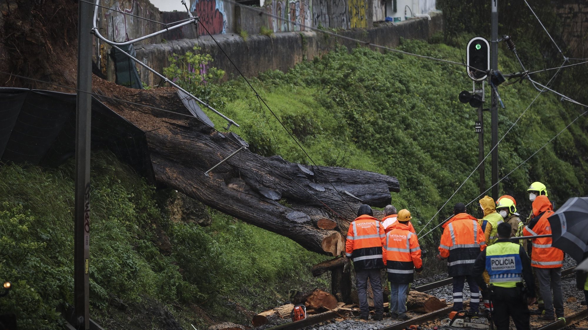 Elementos dos bombeiros retiram uma árvore que caiu na linha de comboio em São João do Estoril devido ao mau tempo, 20 de fevereiro de 2021. RODRIGO ANTUNES/LUSA
