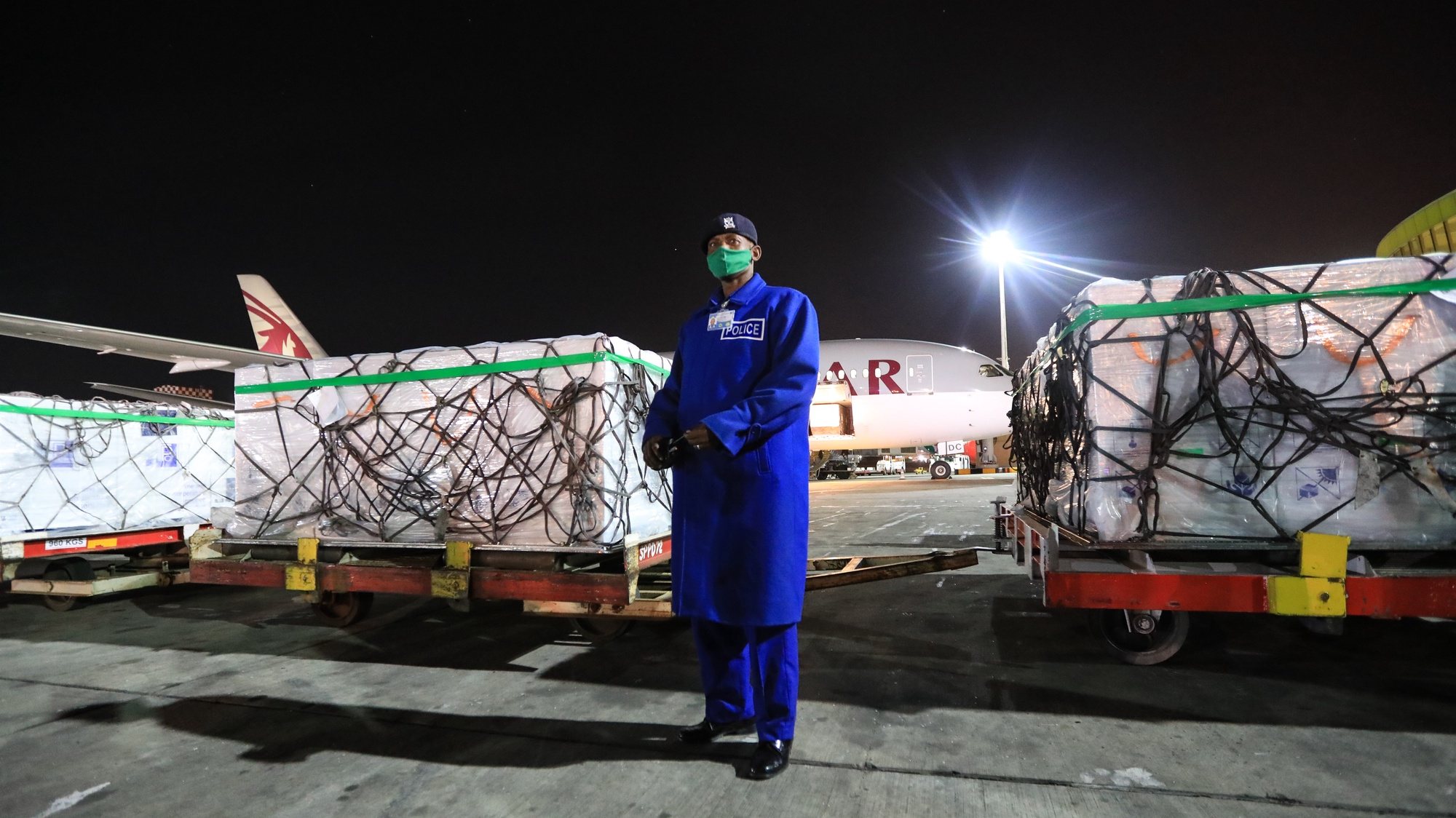 epa09047555 A Kenya police officer (C) stands guard next to some of the first batch of 1.02 million doses of Oxford/AstraZeneca COVID-19 vaccines after being unloaded from a plane upon their arrivals at the Jomo Kenyatta International Airport (JKIA), in Nairobi, Kenya, 03 March 2021. Kenya has received its first batch of COVID-19 vaccines, becoming the first East African country to receive vaccines through COVAX. The East African country is expected to import 24 million doses in couple of months. The first batch are expected to be prioritized to be vaccinated to the health sector workers and security personnel among others.  EPA/Daniel Irungu