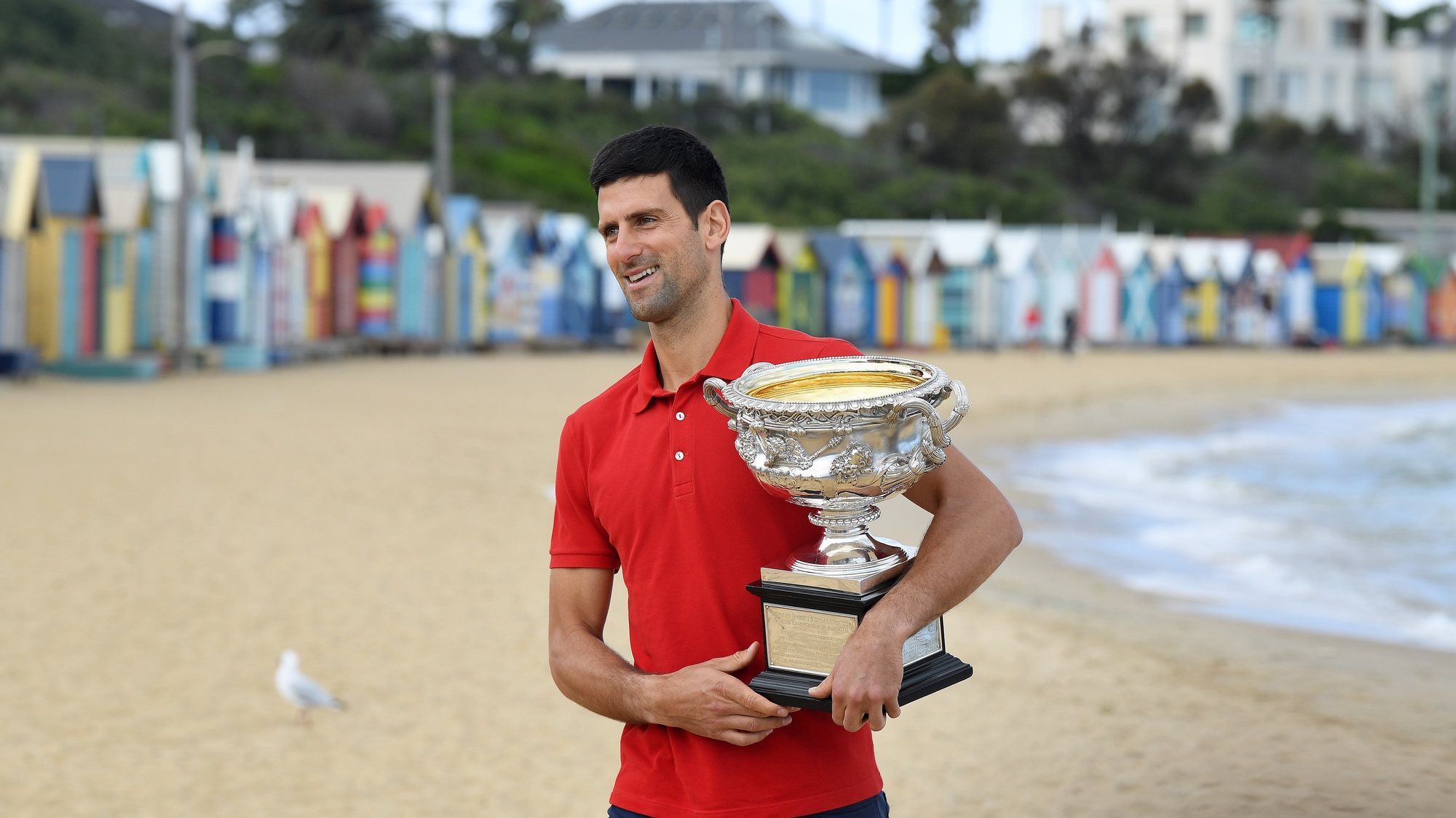 epa09028949 Novak Djokovic of Serbia walks on Brighton Beach with the Norman Brookes Challenge Cup following his men&#039;s singles finals win against Daniil Medvedev of Russia at the Australian Open grand slam tennis tournament, in Melbourne, Australia, 22 February 2021.  EPA/DAVE HUNT AUSTRALIA AND NEW ZEALAND OUT