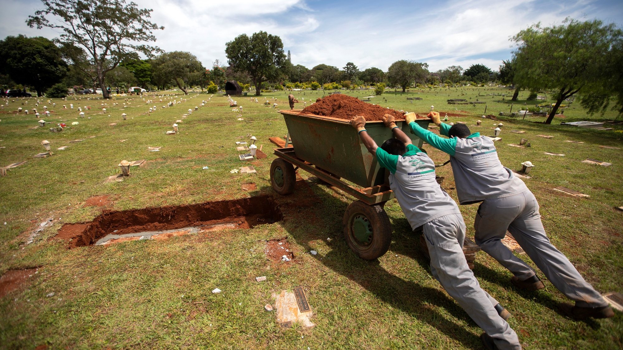 epaselect epa09091972 Workers push a container with sand, in the Campo de Esperanza cemetery, Brasilia, Brazil, 23 March 2021. Brazil borders on 300,000 deaths due to Covid-19, while the risk of shortages of essential drugs for patients with more serious conditions persists in the face of the increasing number of hospitalizations.  EPA/Joedson Alves
