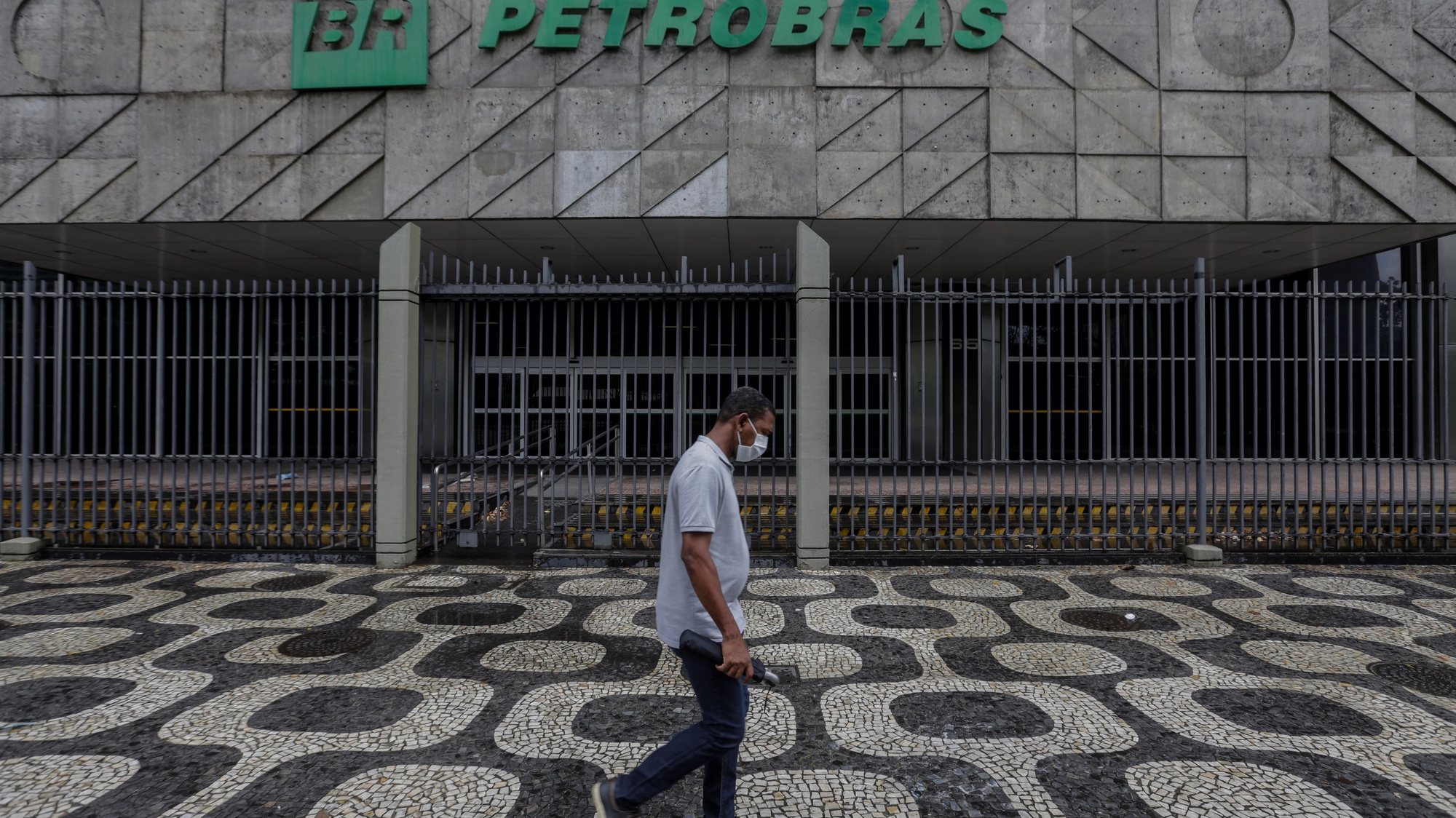 epa09030274 A person walks in front of the Petrobras headquarters in Rio de Janeiro, Brazil, 22 February 2021. The Brazilian president has opened a new crisis in Petrobras by announcing a retired Army general as the new president of the state oil company, which sank in the stock market, and raised doubts about his commitment to economic liberalism.  EPA/Antonio Lacerda
