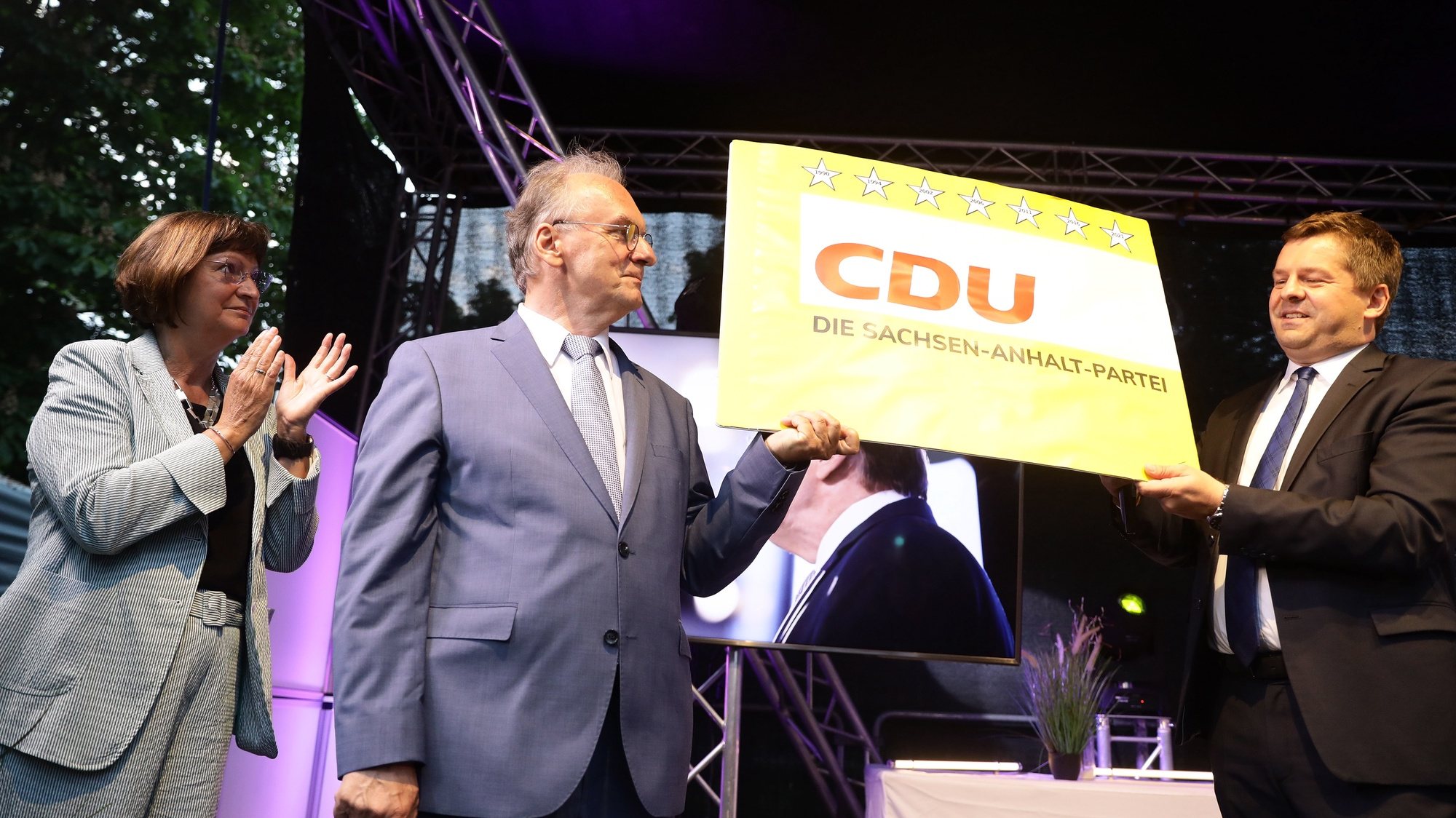 epa09251925 The leading candidate of the German Christian Democratic Party (CDU), Reiner Haseloff (C), his wife Gabriele (L) and the leader of the Saxony-Anhalt CDU, Sven Schulze, hold a poster with the inscription &#039;CDU, The Saxony-Anhalt Party&#039;,  at the election results party of the CDU following the Saxony-Anhalt state elections in Magdeburg, Germany, 06 June 2021. The regional election in Germany&#039;s federal state of Saxony-Anhalt is the last before general elections in September and is considered a trend indicator.  EPA/FILIP SINGER