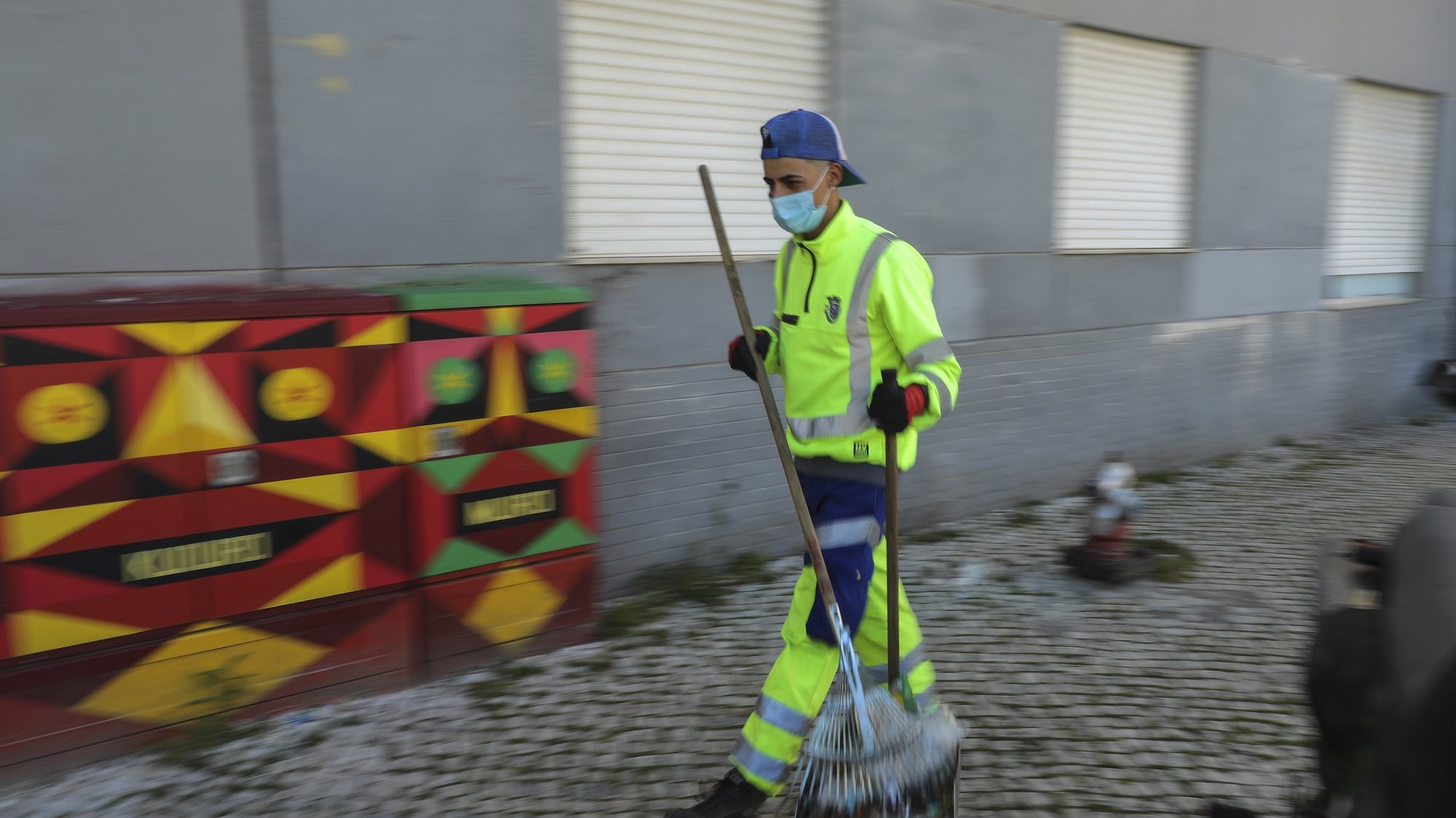 Um trabalhador de limpeza municipal varre as ruas do Bairro da Cruz Vermelha em período de Estado de Emergência devido à pandemia provocada pela covid-19, em Lisboa, 3 de abril de 2020. (ACOMPANHA TEXTO DE 6 DE ABRIL DE 2020). MIGUEL A. LOPES/LUSA