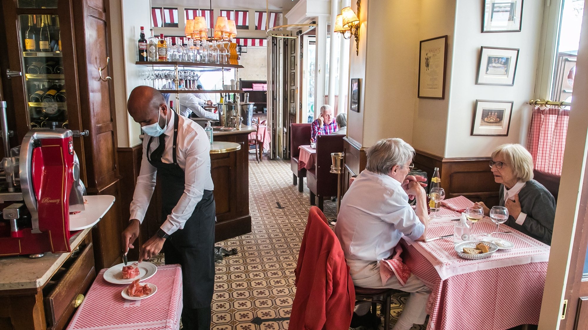 epa09257216 An employee wearing a face mask cuts ham slices at the &#039;La Fontaine de Mars&#039; restaurant on the day of the reopening of the bars and restaurants inside and on terraces in Paris, France, 09 June 2021. France reopens bars and restaurants nationwide after easing of coronavirus health measures amid the Covid-19 pandemic.  EPA/CHRISTOPHE PETIT TESSON