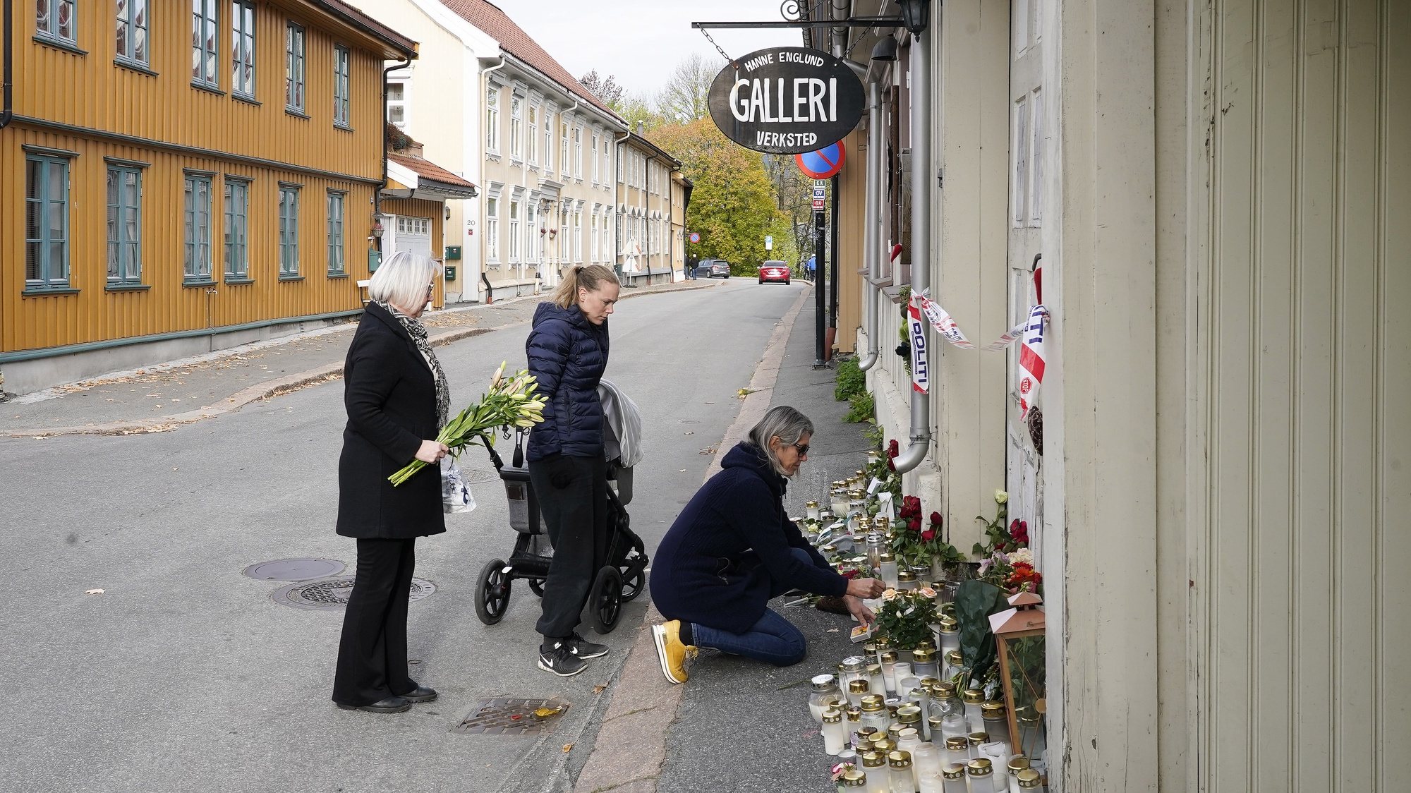 epa09529977 Three students by artist Hanne Englund lay flowers in front of her house in Kongsberg, Norway, 18 October 2021. A man has been arrested and charged with killing five and injuring three other people in Kongsberg center.  EPA/Terje Bendiksby  NORWAY OUT NORWAY OUT