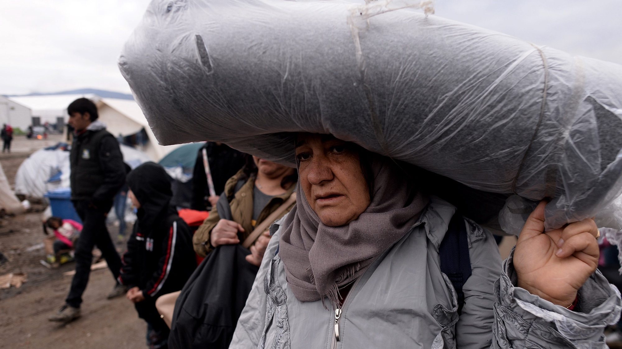 epa05214864 A migrant carries a blanket, at a refugee camp at the border between Greece and the Former Yugoslav Republic of Macedonia (FYROM) near Idomeni, Northern Greece, 15 March 2016. Greek Prime Minister Alxis Tsipras on 15 March called on refugees to allow the Athens government to move them from the Idomeni camp to other reception centers, stressing that the borders are closed and will not be reopened in the near future. Greece has registered more than 44,000 migrants that are currently trapped due to entry restrictions already imposed by Macedonia in recent months, by denying entry to all those who are considered economic migrants, prohibiting the passage of Afghans, and finally denying entry to all Syrians and Iraqis who are not from combat areas.  EPA/NAKE BATEV  EPA/NAKE BATEV