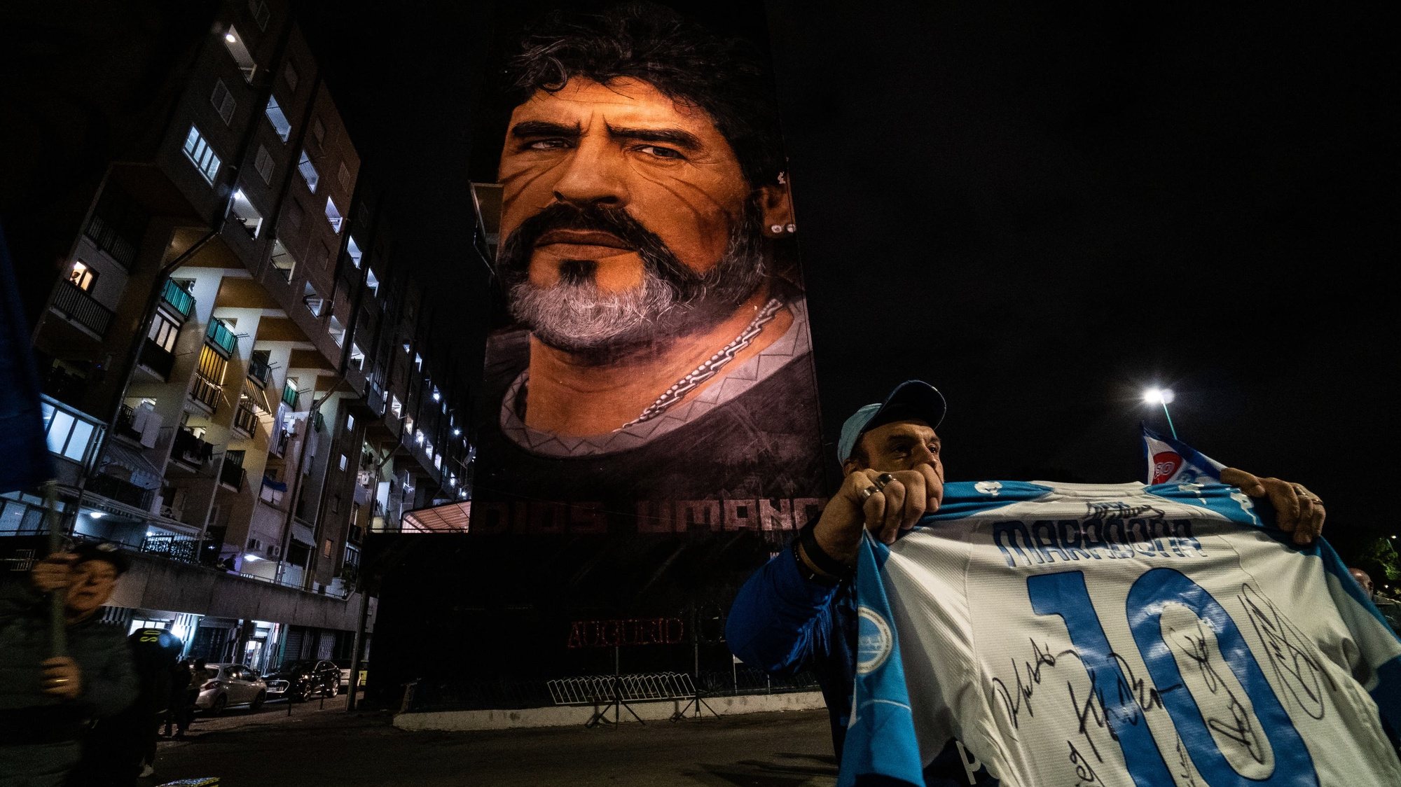 epa09555571 Fans celebrate Diego Armando Maradona&#039;s birthday anniversary next to a mural, made by Italian-Dutch street artist Jorit, depicting the late Argentine football legend in Naples, southern Italy, late 30 October 2021. Maradona passed away on 25 November 2020 at the age of 60.  EPA/CESARE ABBATE
