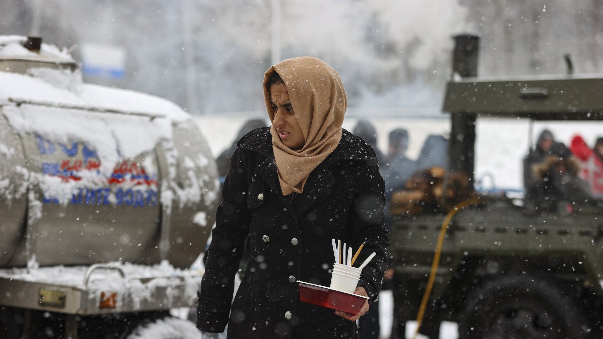 epa09599114 A woman walks to collect food provided by Belarusian servicemen at a camp at the Belarusian-Polish border near the Bruzgi-Kuznica Bialostocka border crossing, in the Grodno region, Belarus, 23 November 2021. Asylum-seekers, refugees and migrants from the Middle East arrived at the Belarusian-Polish checkpoint of Bruzgi-Kuznica aiming to cross the border. Thousands of people who want to obtain asylum in the European Union have been trapped at low temperatures at the border since 08 November.  EPA/STRINGER