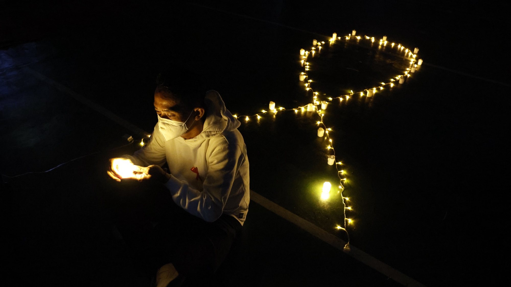epa09614446 An activist holds an electric candle during a vigil to mark World Aids Day in Jakarta, Indonesia, 01 December 2021. World AIDS Day, observed annually on 01 December, is dedicated to raising awareness against the spread of AIDS and HIV infections.  EPA/MAST IRHAM