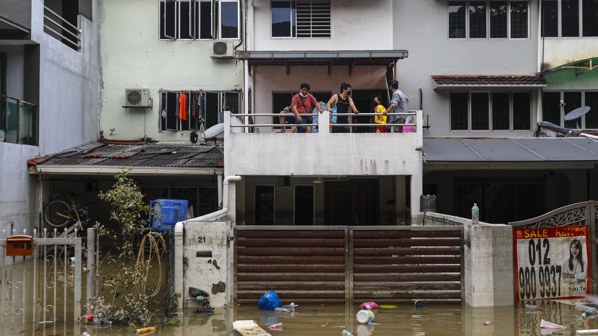 epa09652260 A family look on outside from their house after floods struck Taman Sri Muda, Shah Alam district, some 40km from Kuala Lumpur, Malaysia, 21 December 2021. Flooding in Malaysia leaves 17 dead and more than 70,000 displaced after several Malaysian states has been struck by floods caused by two days of heavy rain with many trapped in their vehicles and homes.  EPA/FAZRY ISMAIL
