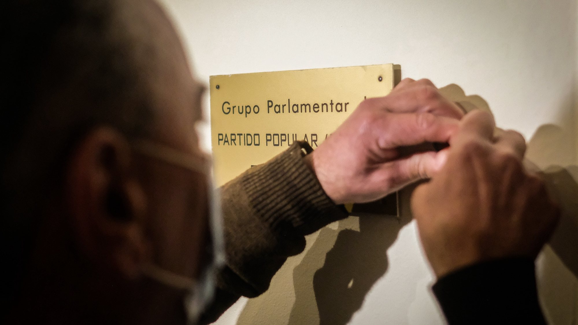 Um carpinteiro remove a placa do grupo parlamentar do CDS-PP na Assembleia da República, em Lisboa, 10 de fevereiro de 2022. O CDS-PP não elegeu nenhum deputado perdendo assim a representação parlamentar pela primeira vez na história do partido. MÁRIO CRUZ/LUSA